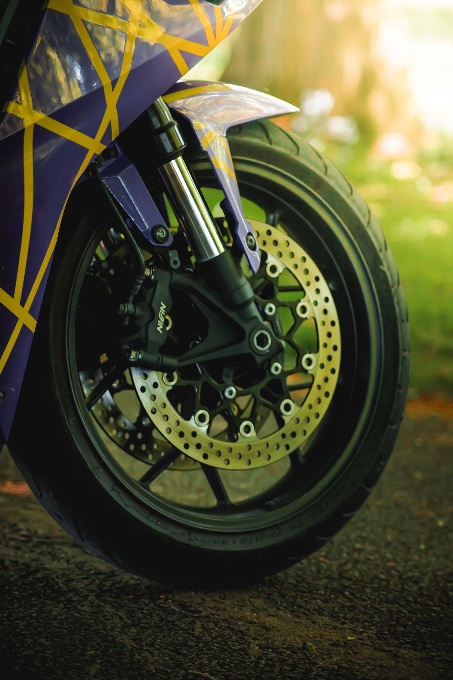Close-up shots of a motorcycle's front disc brake and wheel assembly shown from different angles in warm lighting.