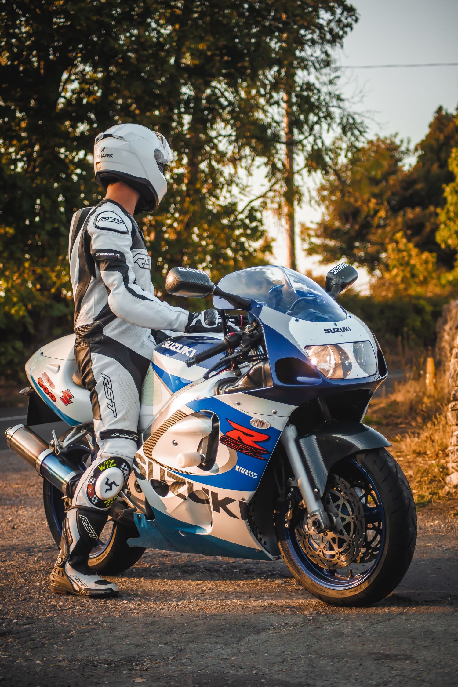 White and blue Suzuki GSX-R sportbike photographed at sunset with golden light illuminating its sleek bodywork.