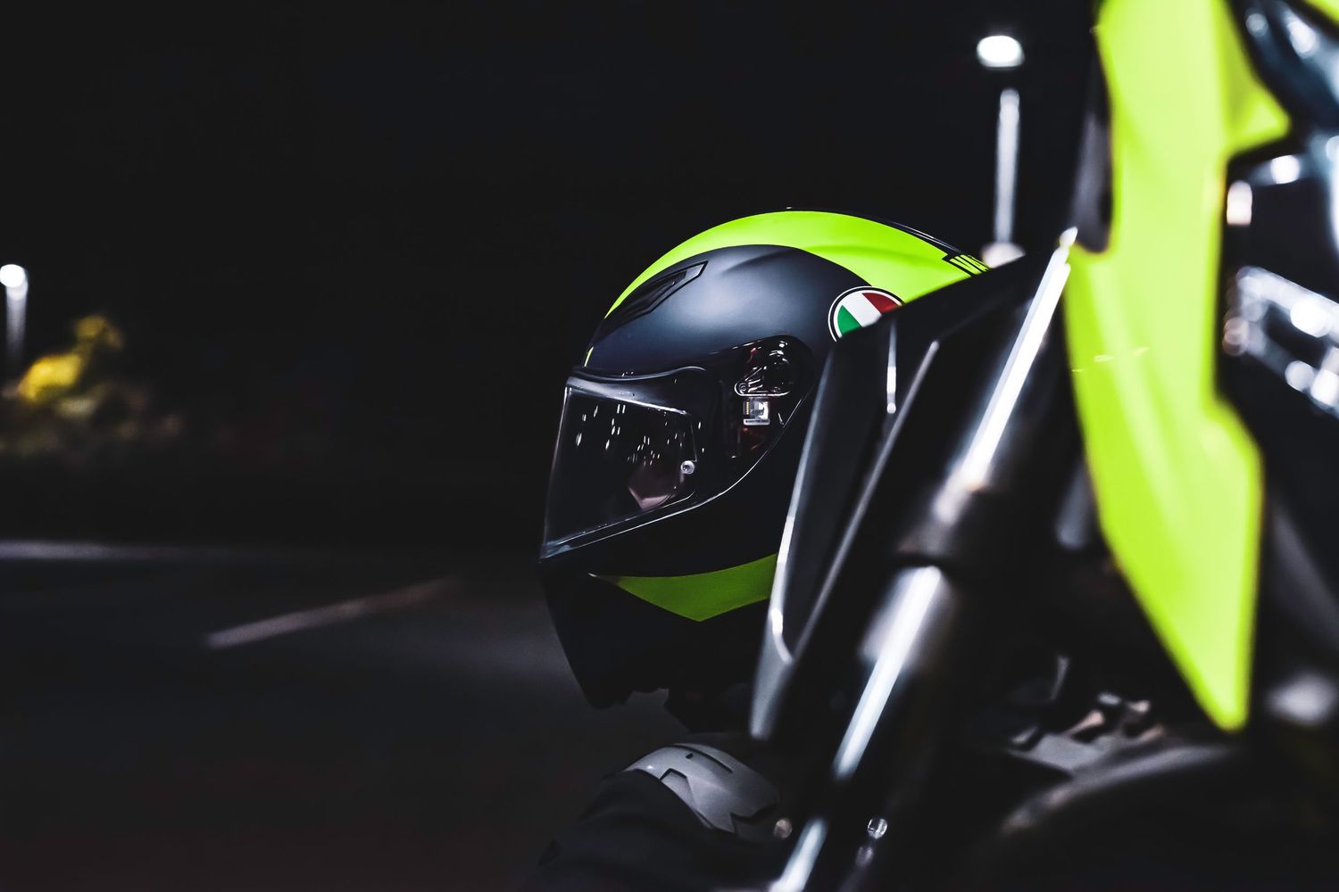A bright green motorcycle handlebar grip and brake lever detail against a dark background.