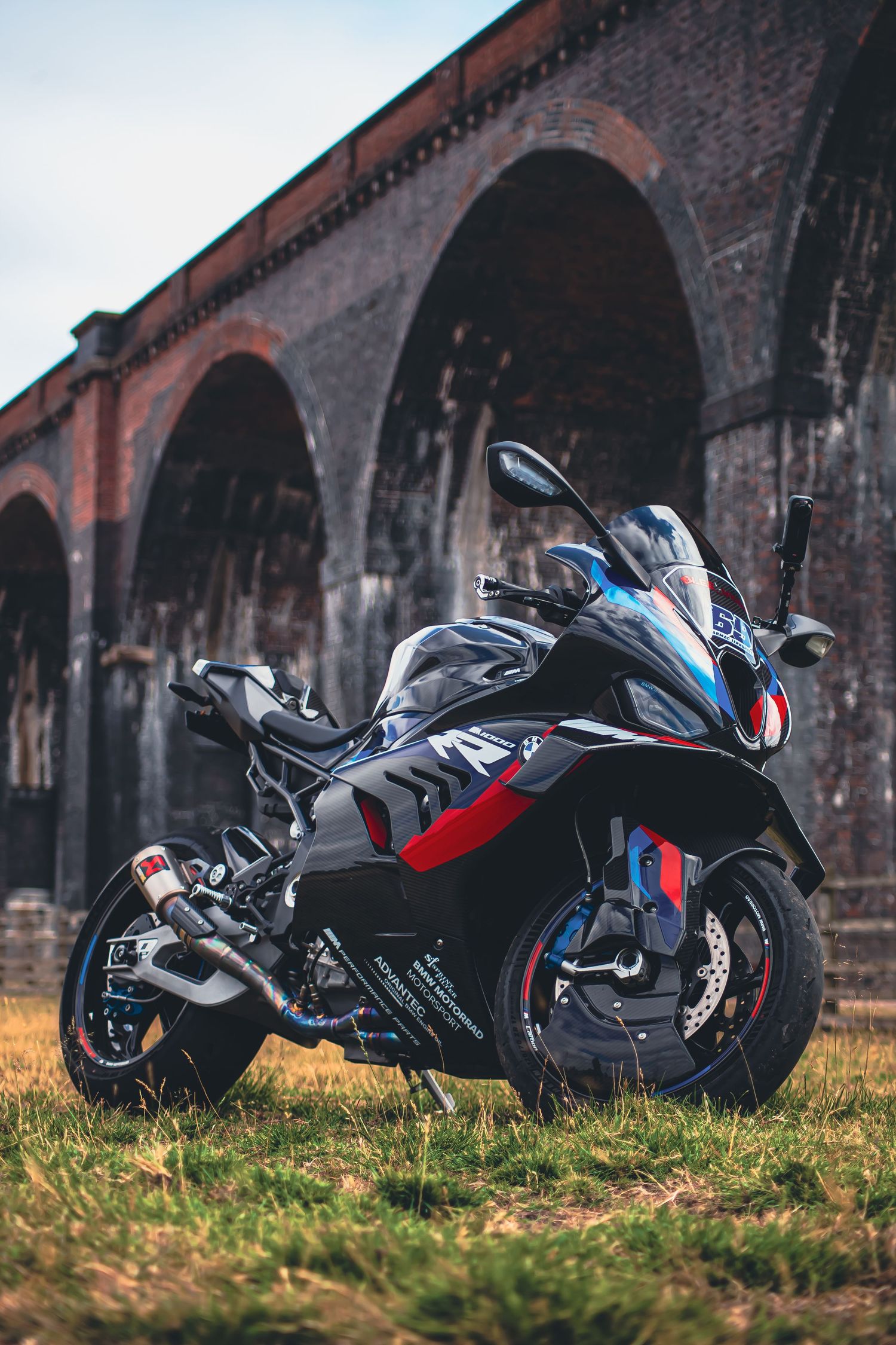 Black sports motorcycle photographed against historic brick railway arches in sequential panoramic shots.