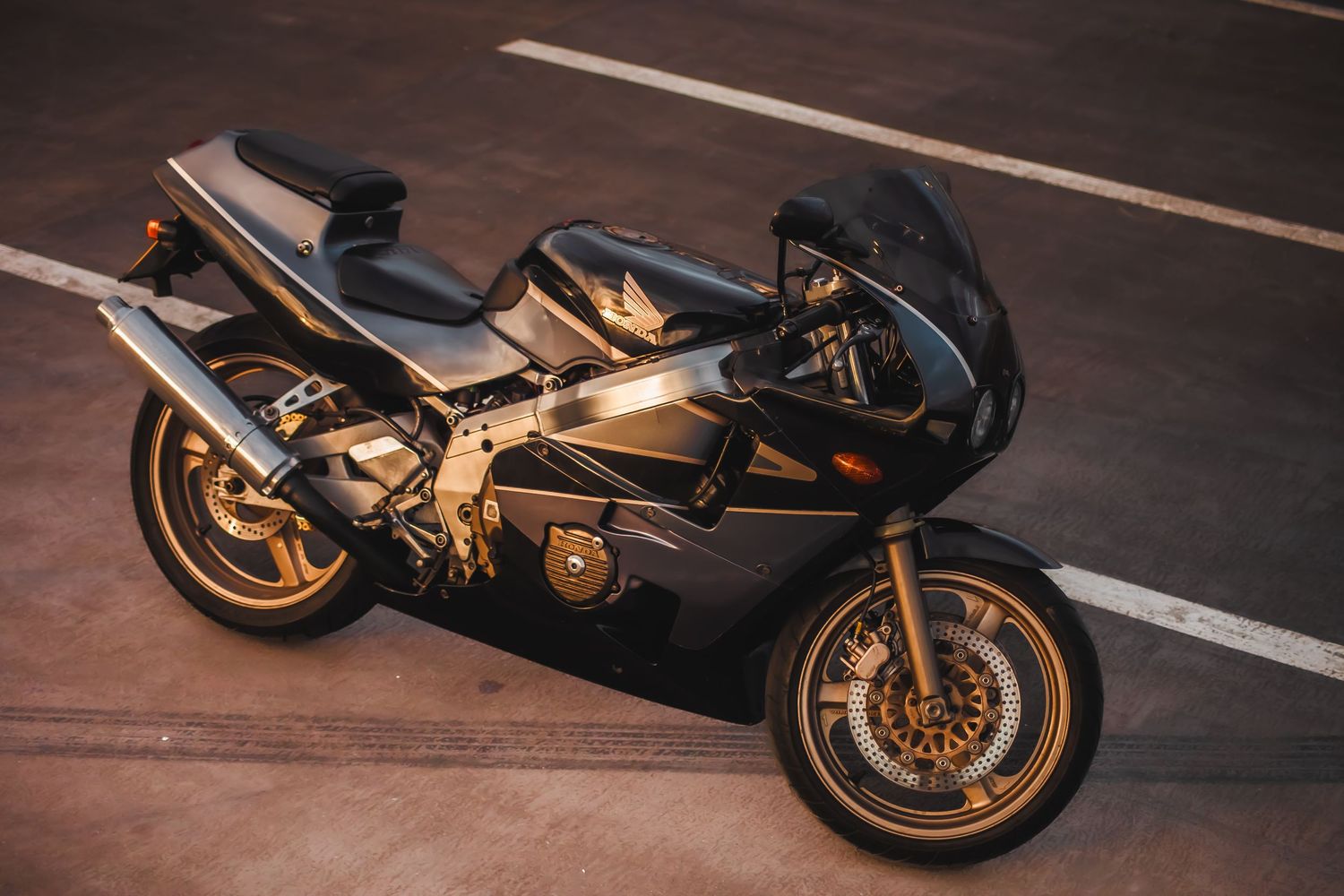Series of sleek black and gold sport motorcycles lined up on a dark wooden surface.
