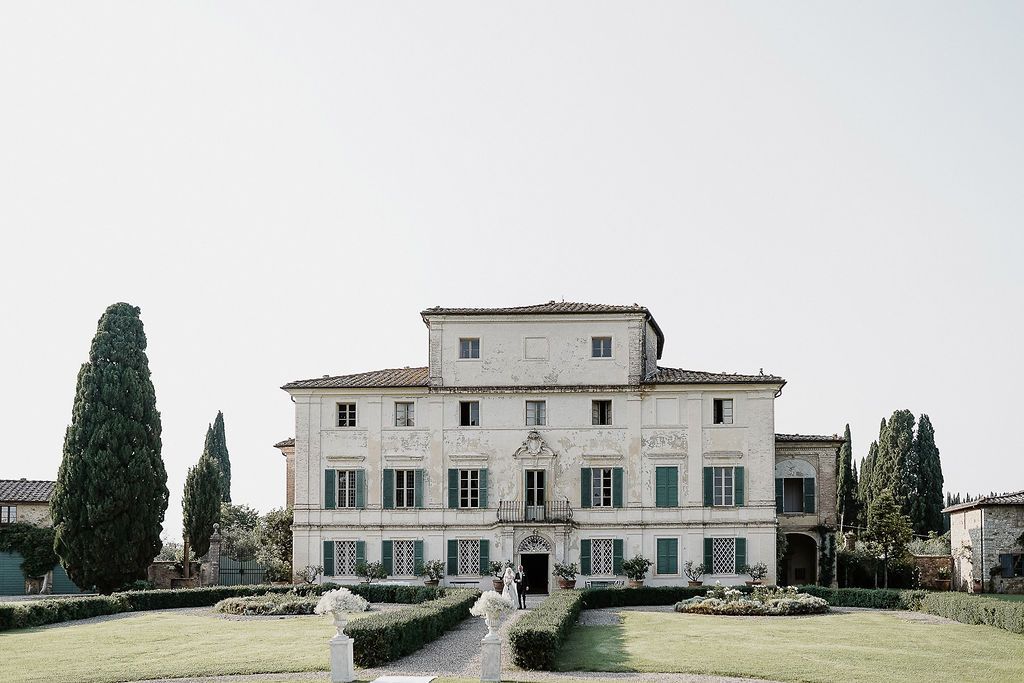 Elegant bride walks with her father at a luxury Tuscan villa by Gradisca Portento. Panoramic wedding photography in a scenic landscape