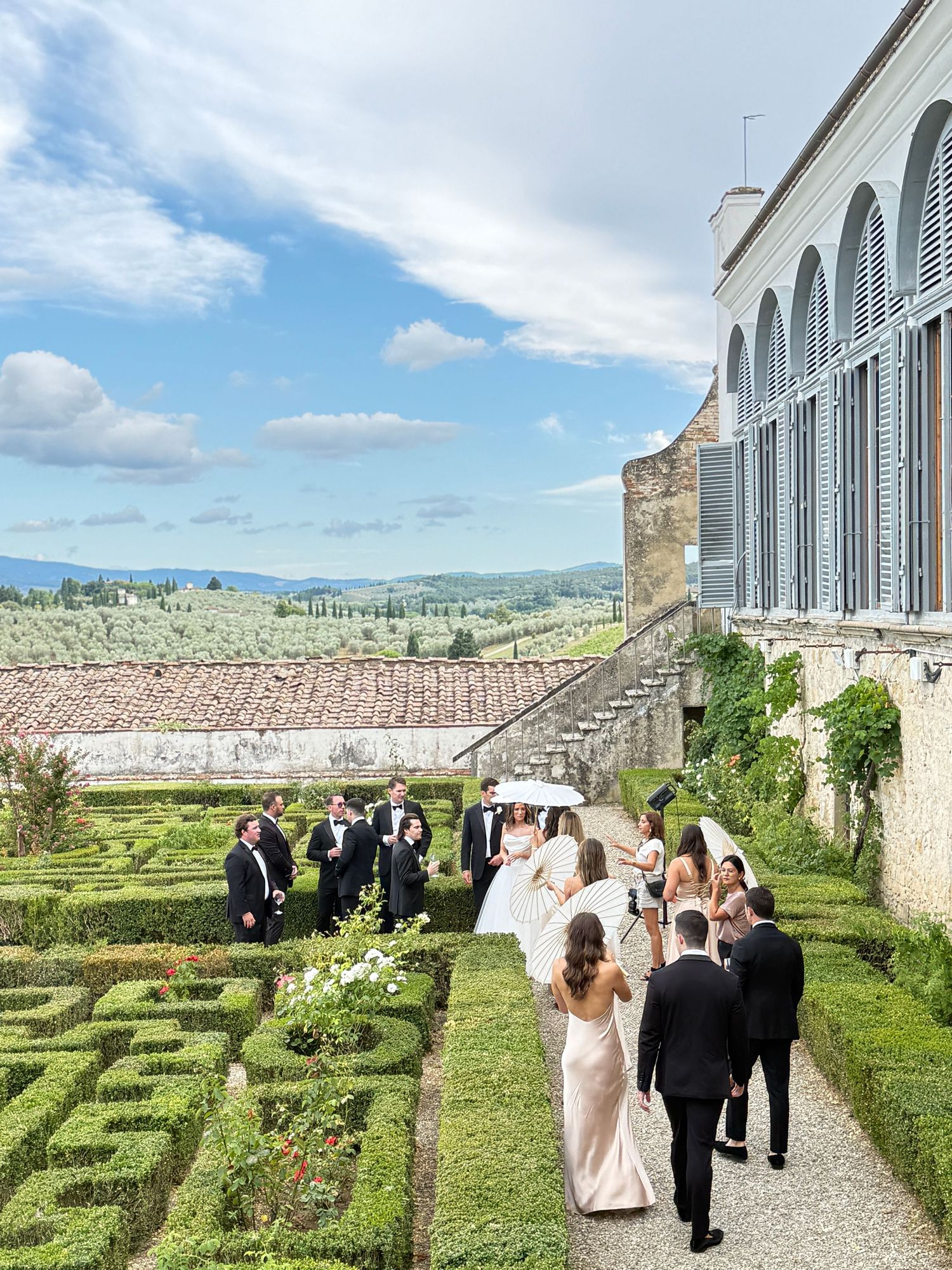 Candid wedding moment at Villa Corsini Firenze. Bride, groom, and wedding party enjoying a conversation in the Italian gardens by Behind Wed