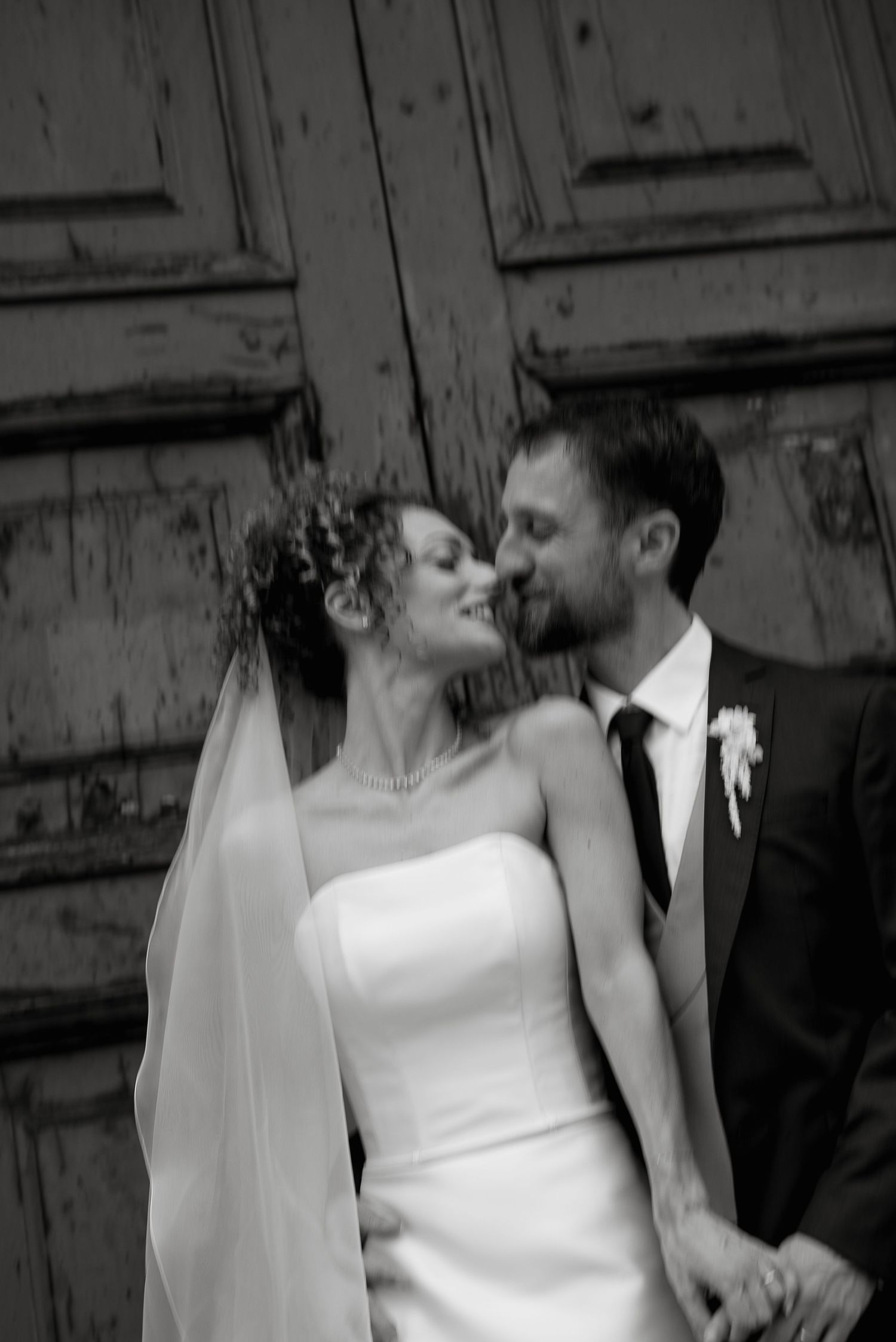 Wedding couple in front of a historic Umbrian church portal. Sophisticated and timeless style by Gradisca Portento.