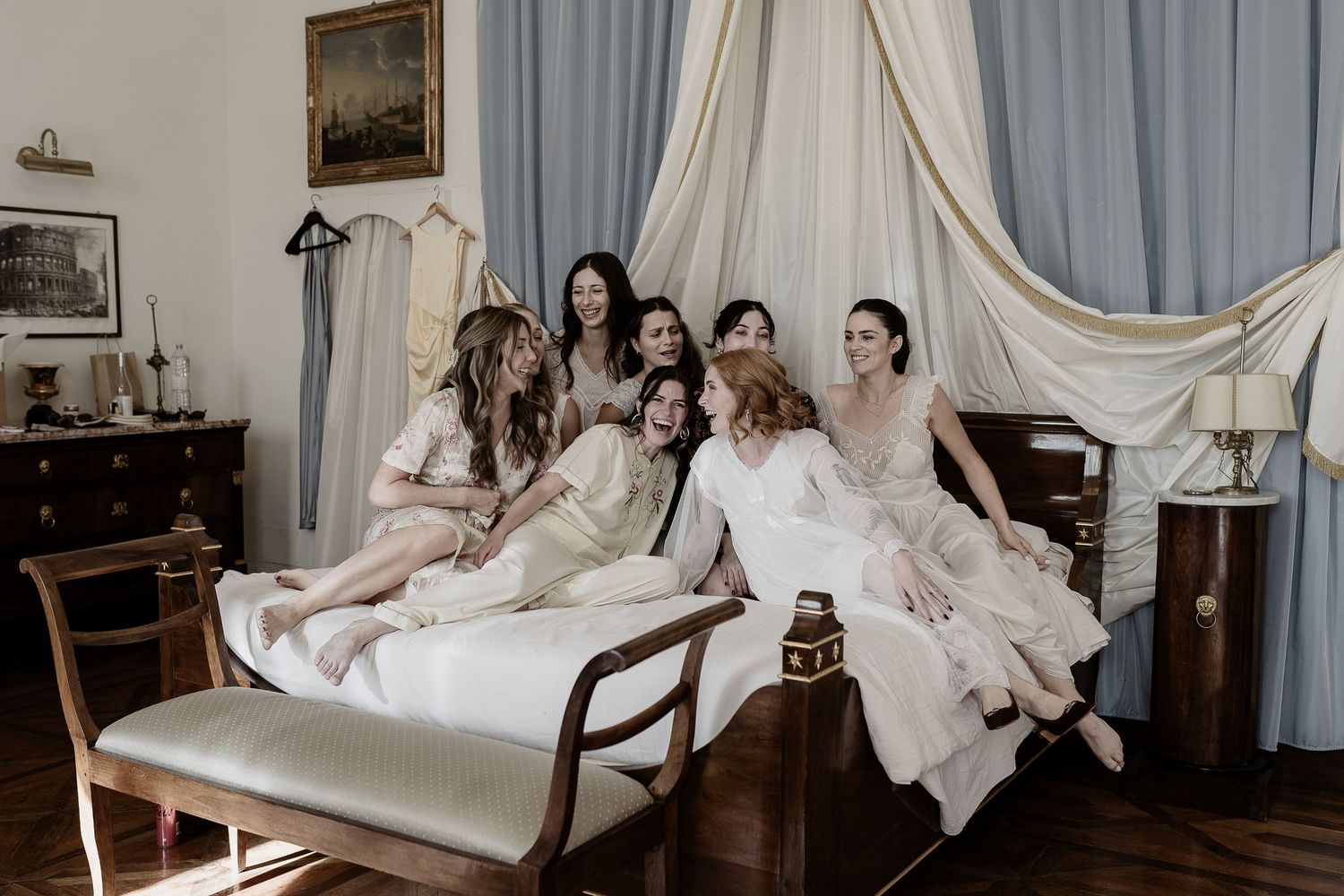 A candid shot of the bride and her bridesmaids on a bed at Villa di Monaciano. Boutique wedding photography in Italy by Gradisca Portento