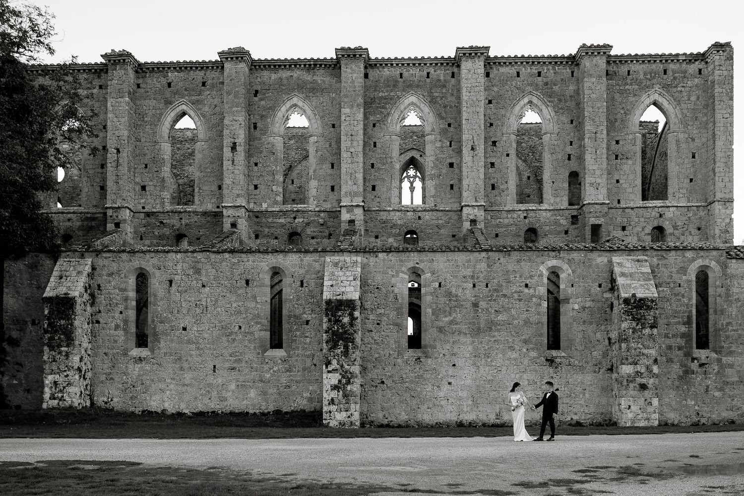 Wide-angle couple portrait at San Galgano Abbey. Exclusive destination wedding at Borgo Santo Pietro, Tuscany.
