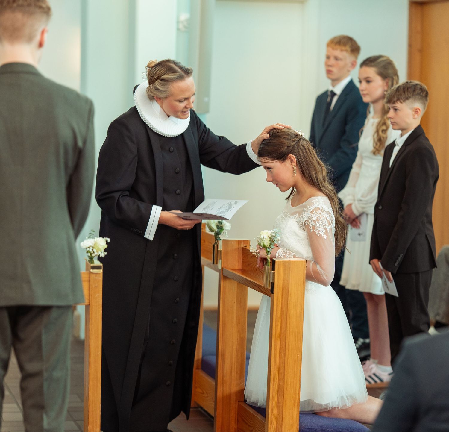 Priest performing a blessing during a religious ceremony in a church with people observing.