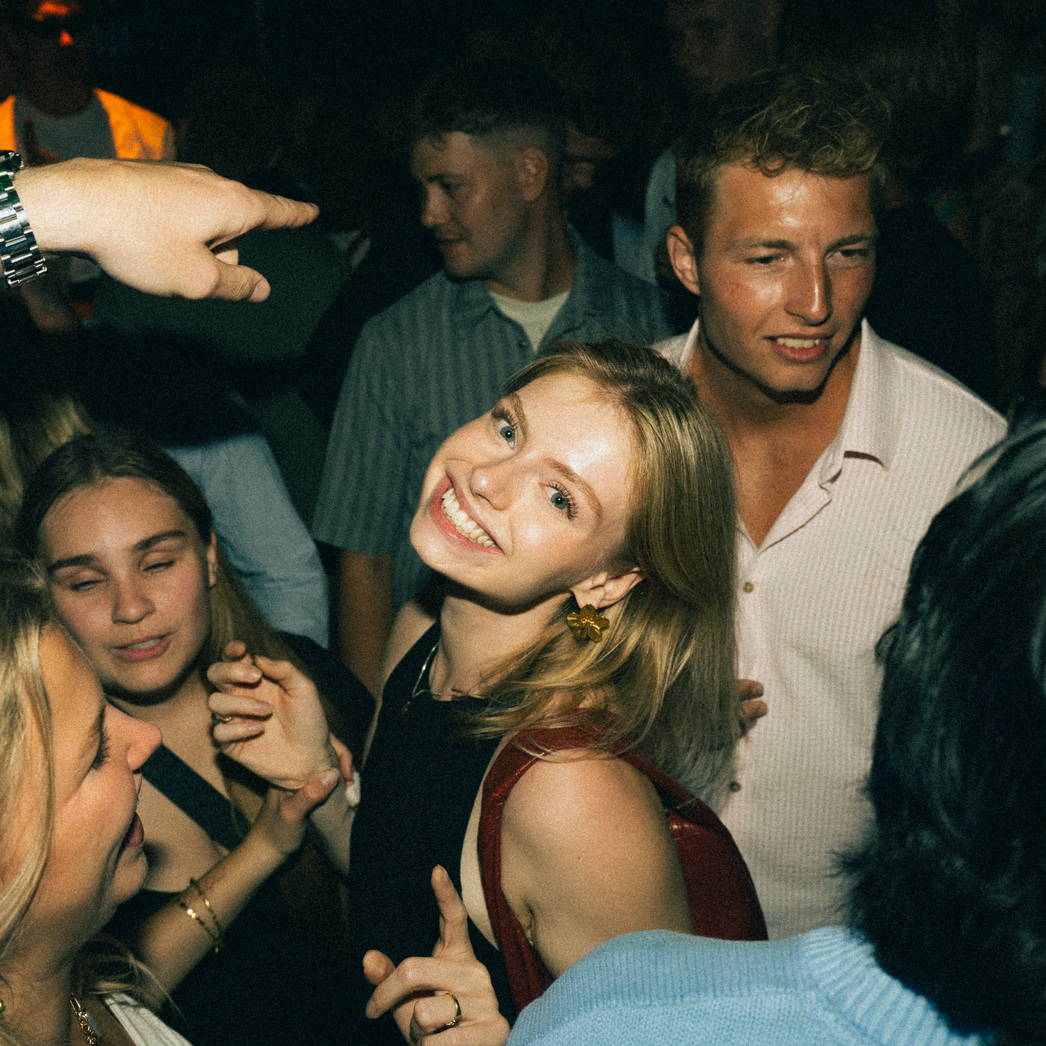 People enjoying themselves and dancing at a nightclub or party with warm lighting in a candid social atmosphere.
