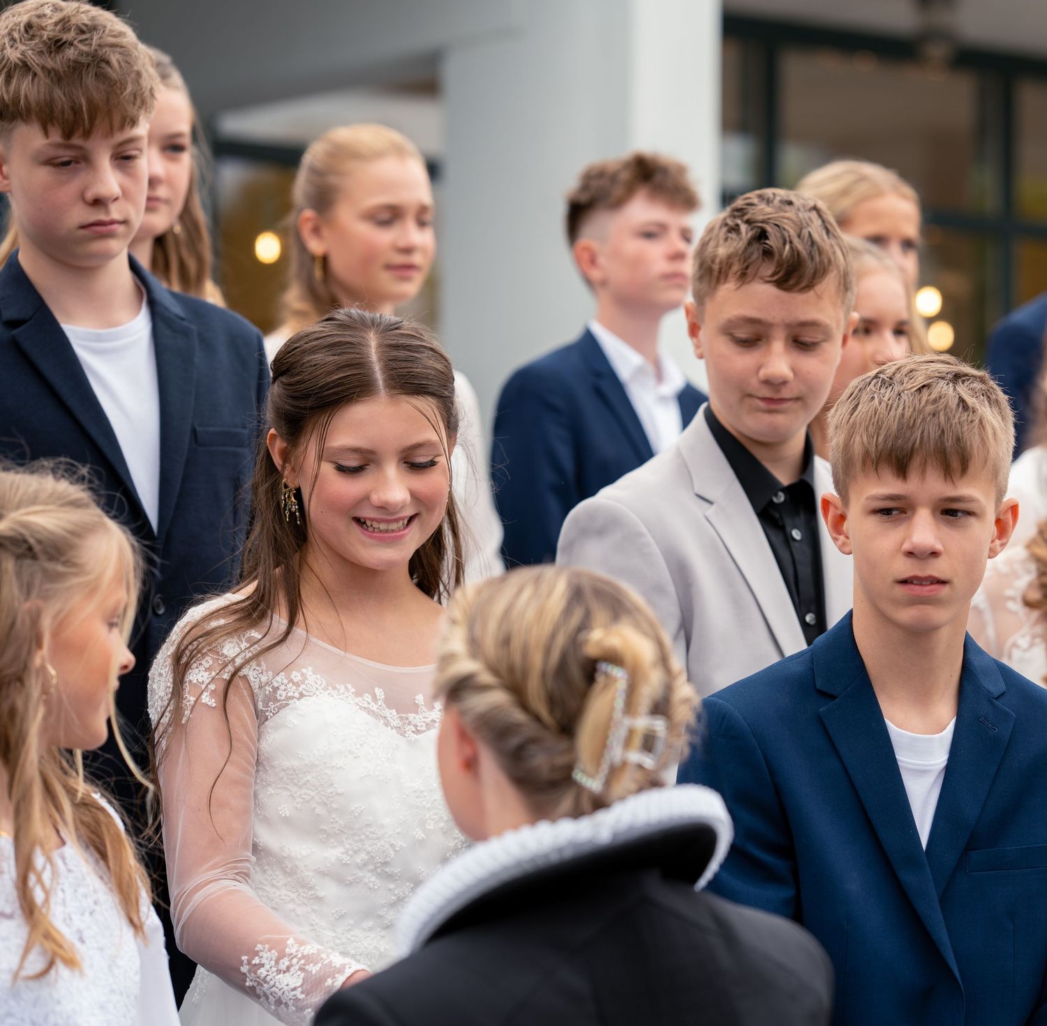 A small gathering of young people in formal attire stand together at a social event.