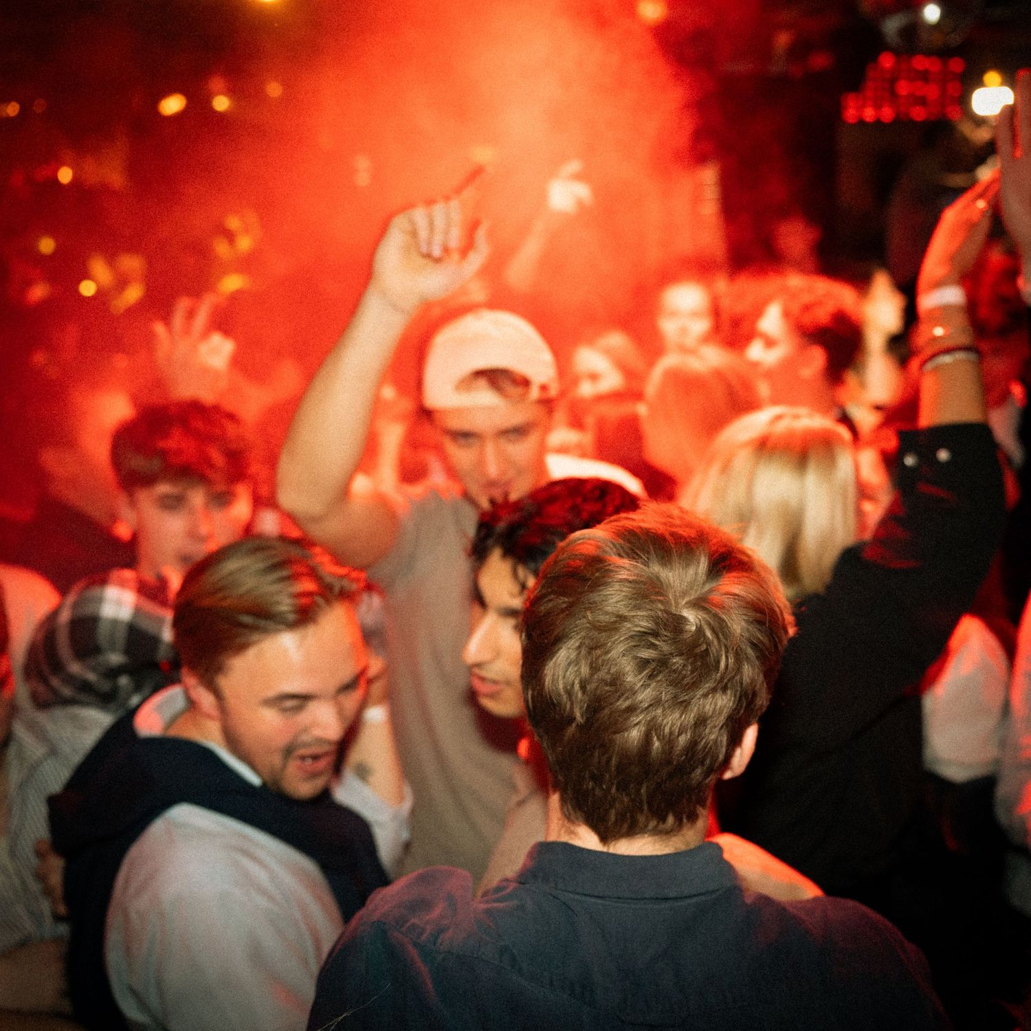 Fyldt dansegulv med rød belysning og folk, der danser på en natklub.