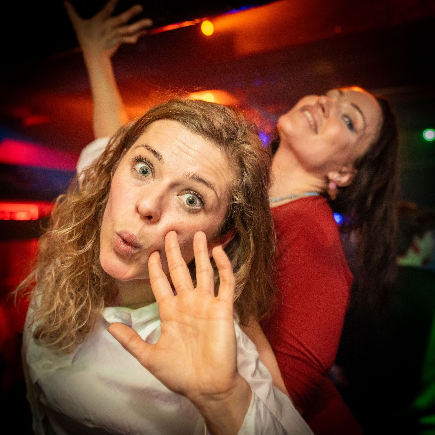 Legesyge festdeltagere laver fjollede ansigter, mens de danser på en natklub med farverigt lys.