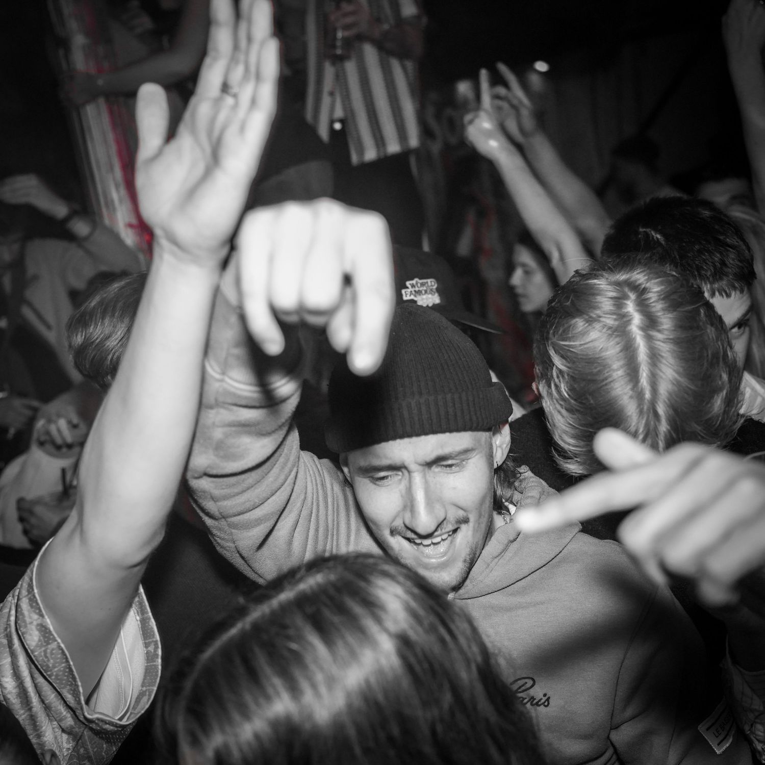 Black and white photo of people dancing and celebrating at a crowded party or club event.
