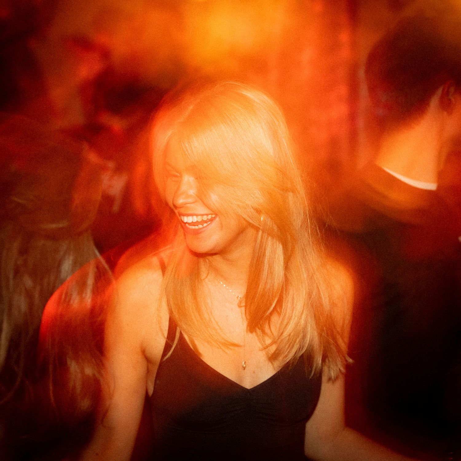 Woman dancing in warm orange lighting at a nightclub party.