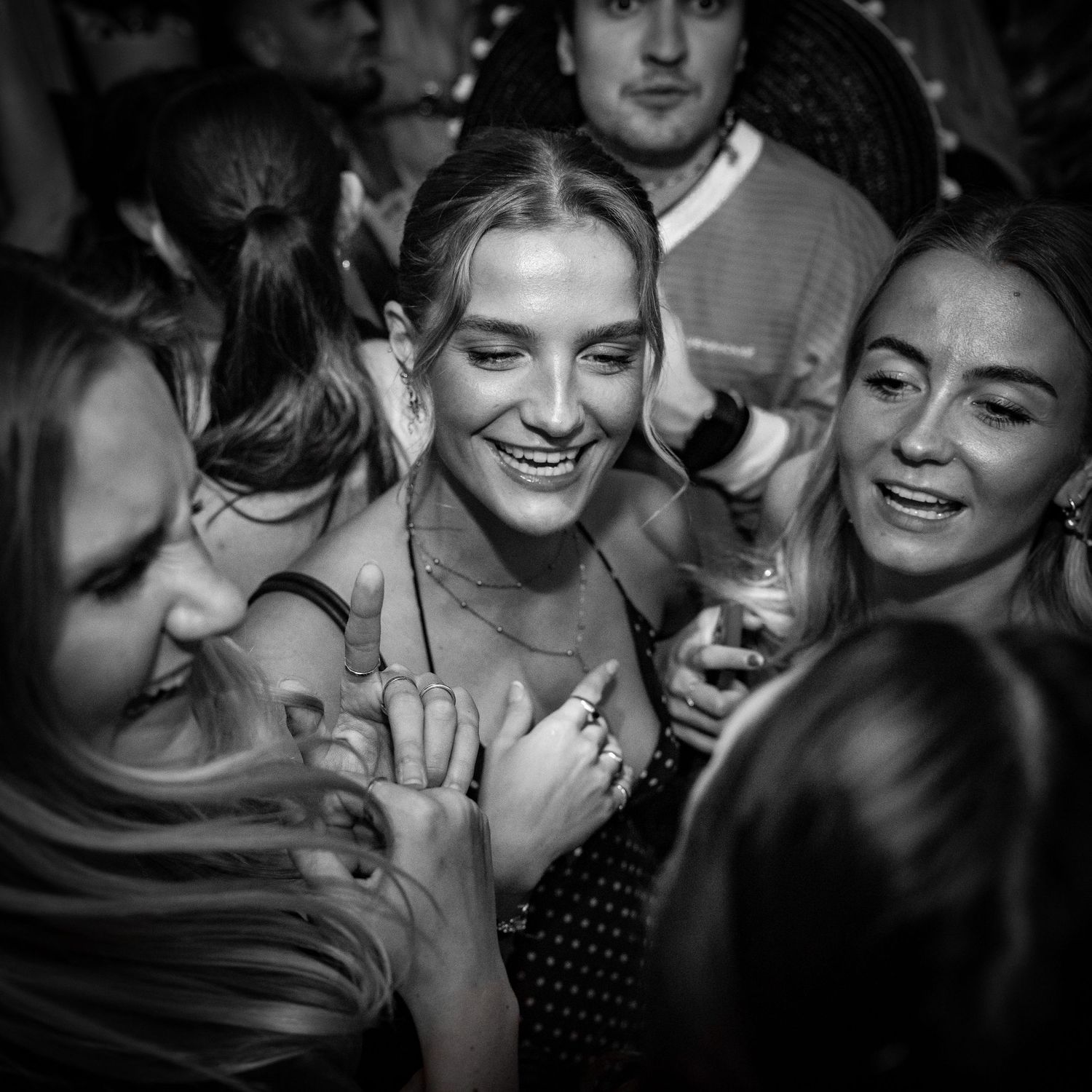 Black and white photo of joyful crowd dancing and celebrating at a nightclub.