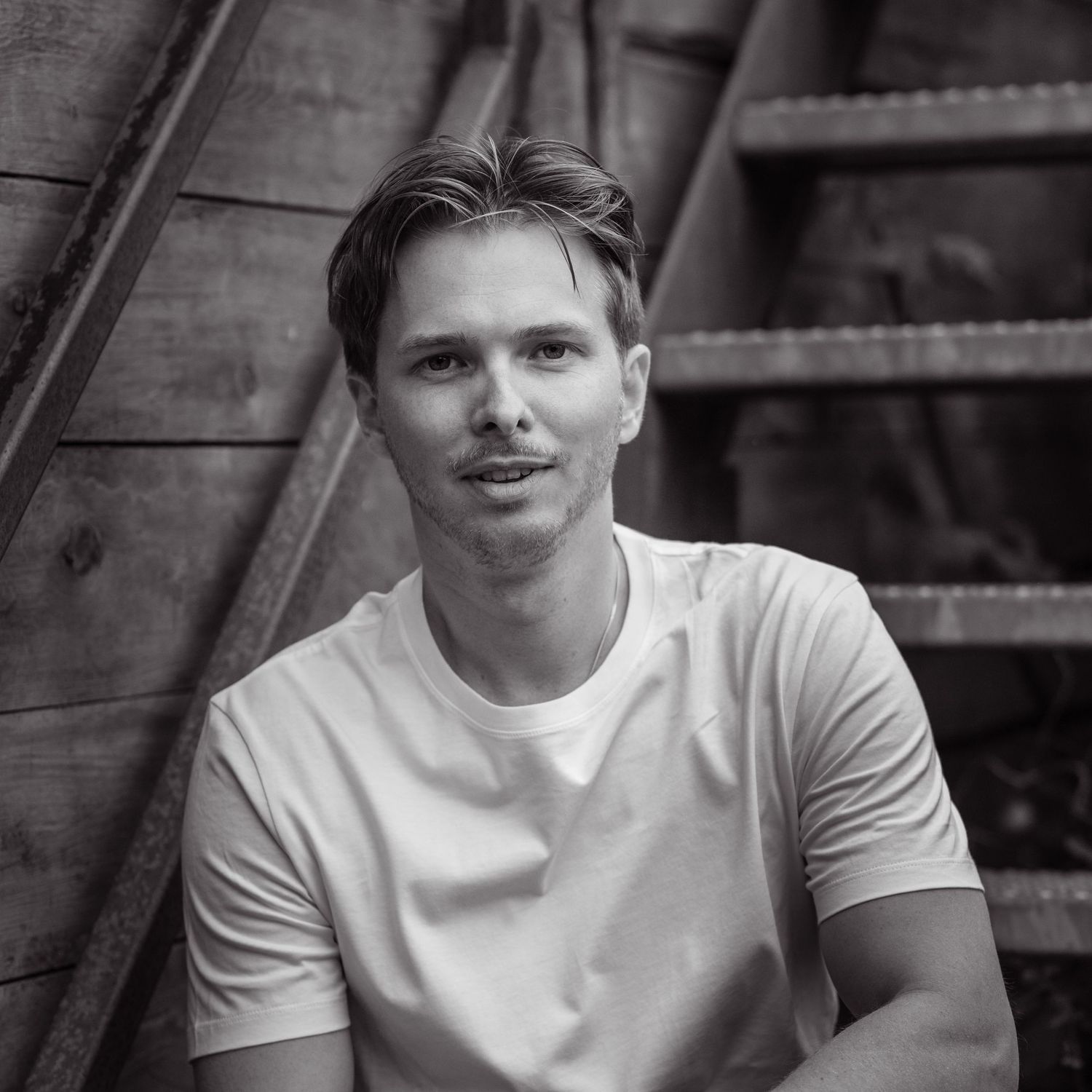 A black and white portrait series showing a person in a white t-shirt from four different angles.