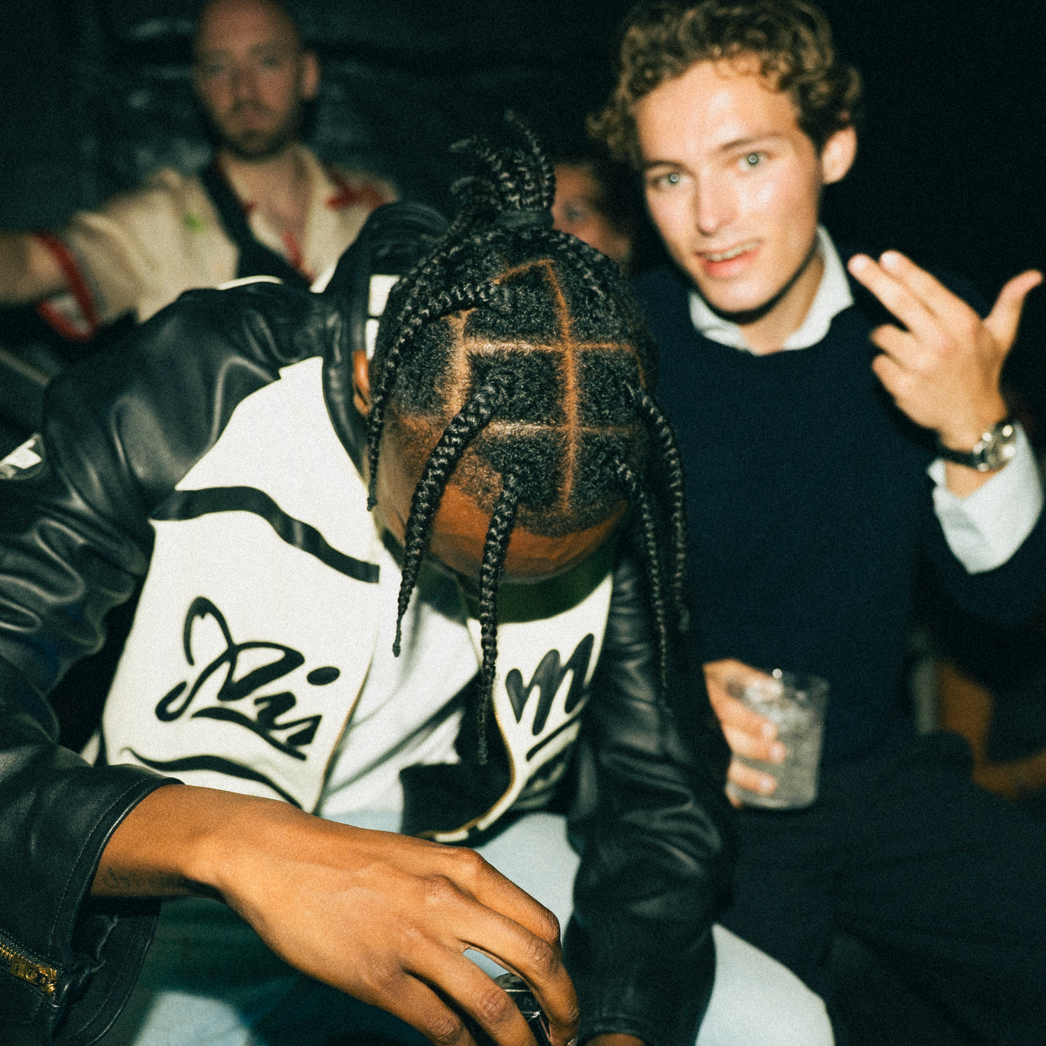 At a party, three people hang out casually together with one person showing intricate braided hairstyle patterns.