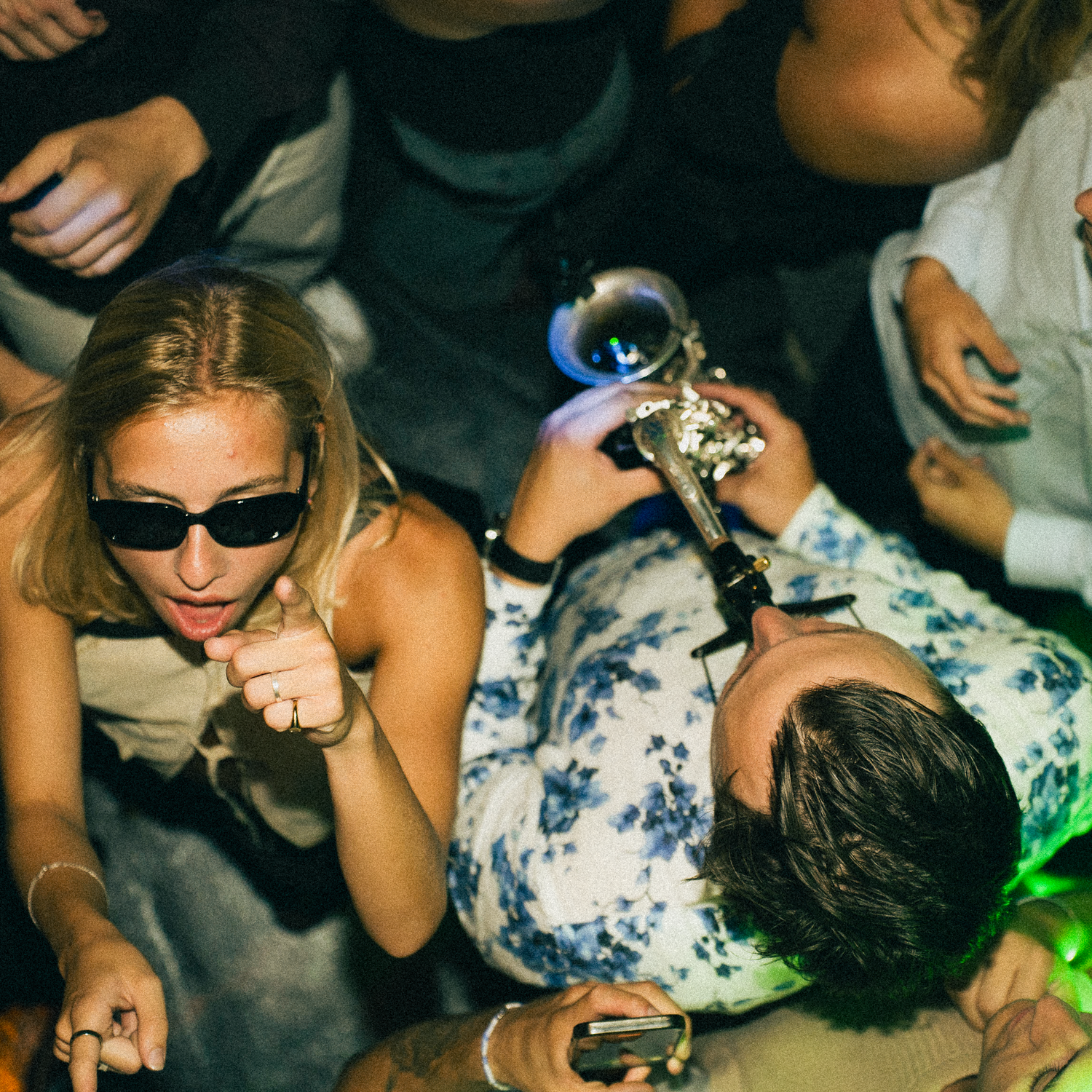 People dancing in a dimly lit nightclub environment with colored lights and glowing accessories.