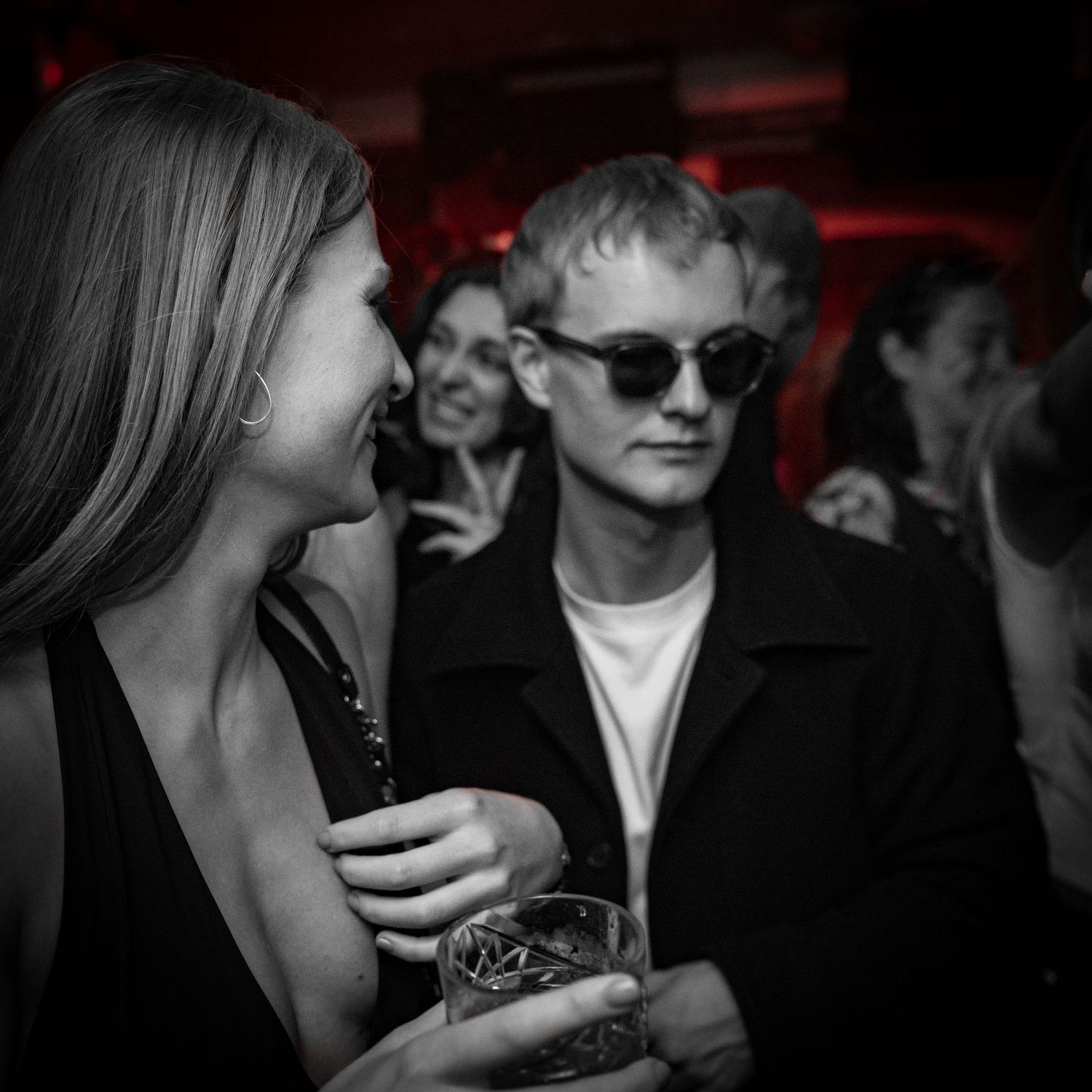 Stylish party scene with people socializing in dimly lit nightclub atmosphere.
