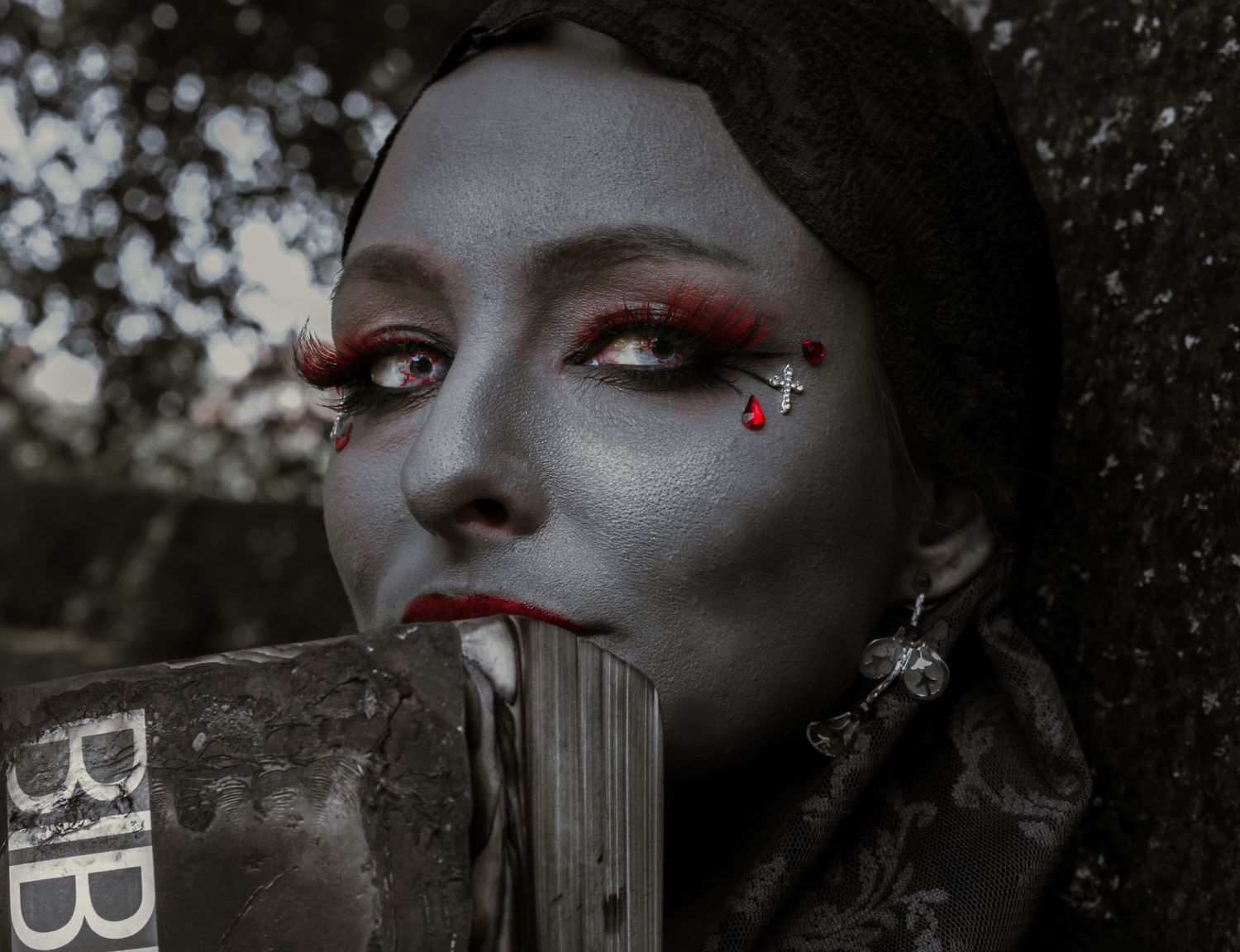 Creative makeup portrait with red eyeshadow and jewels in dramatic lighting.