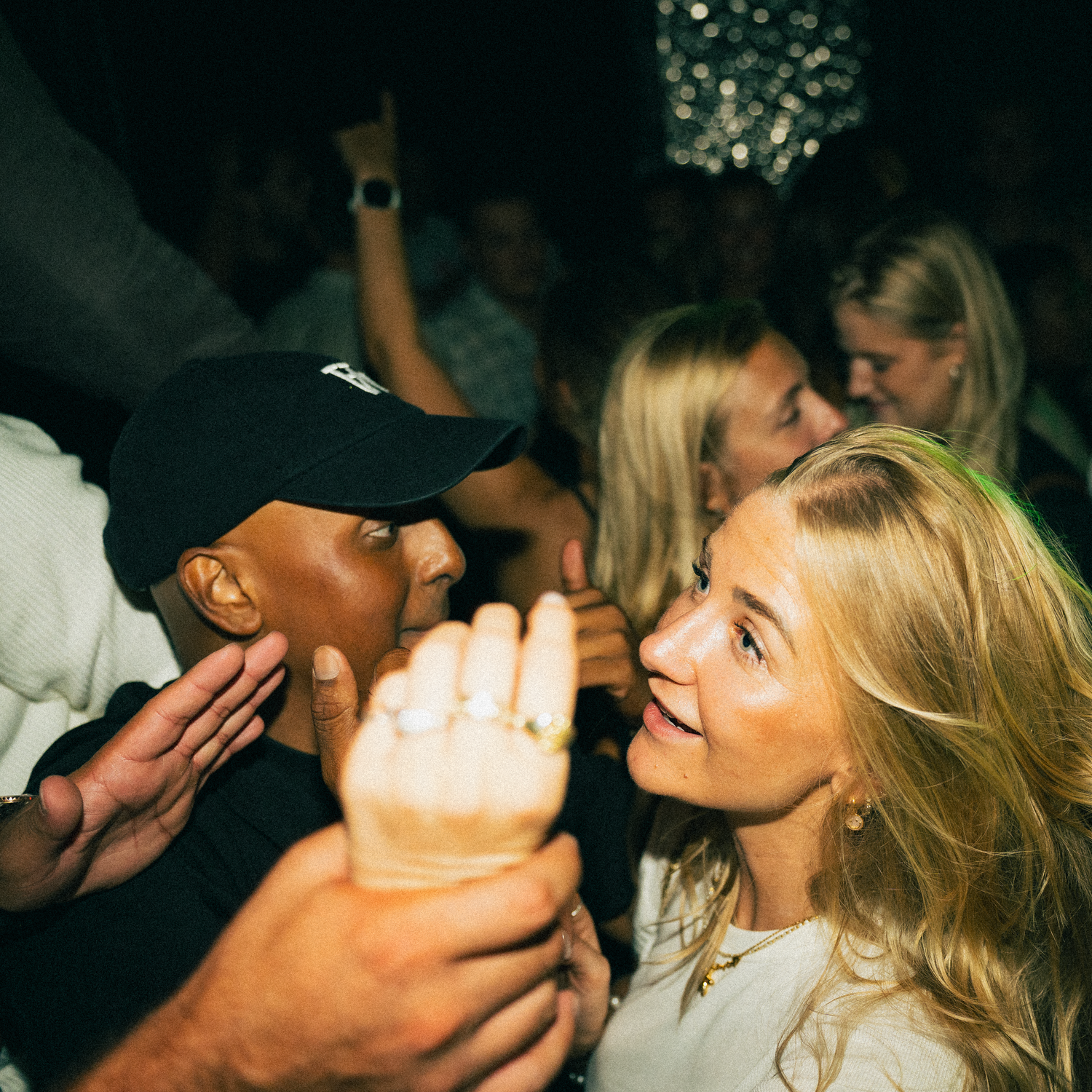People dancing and socializing at a lively nightclub party with dynamic lighting.