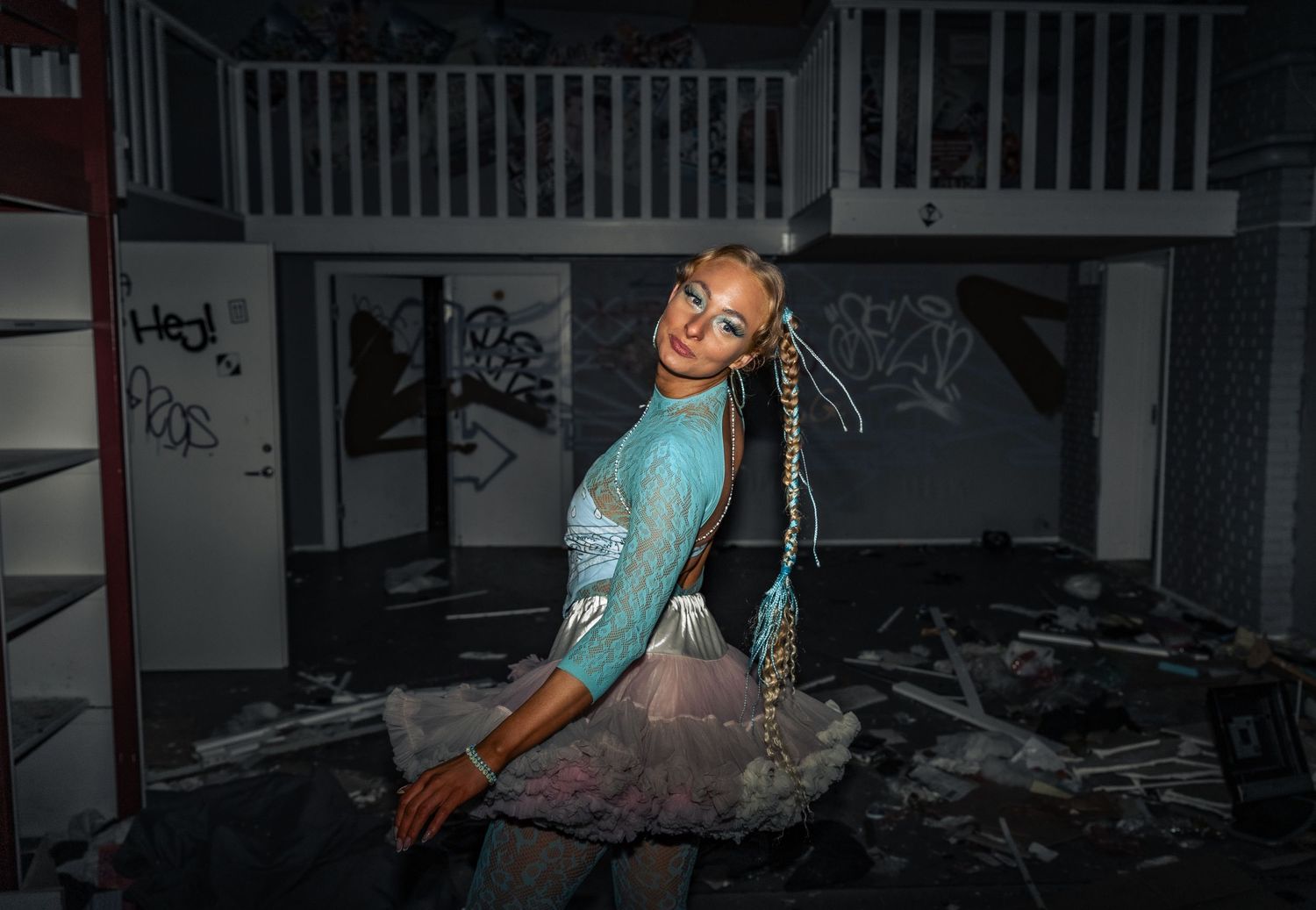 Dynamic shot of a dancer in turquoise attire performing in an abandoned space.