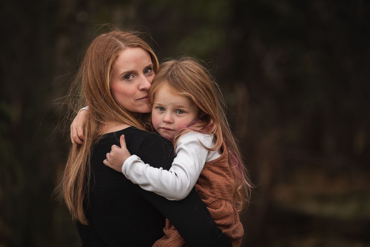 Mother and child sharing tender embrace against dark background.