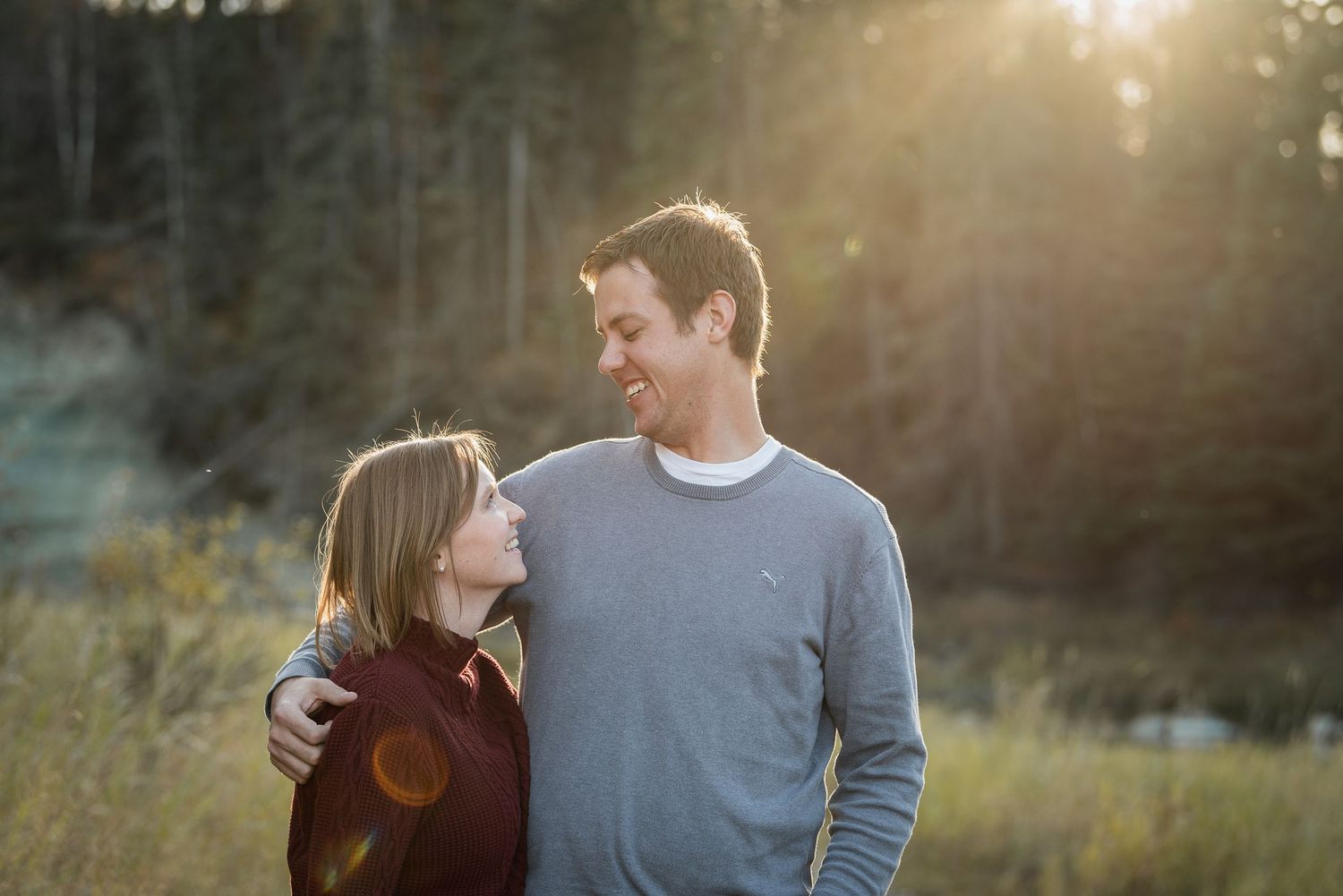 A couple sharing a joyful moment together in a sunlit meadow during golden hour.
