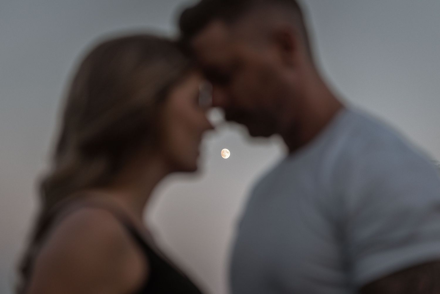 Two silhouettes share an intimate moment against a soft blurred background.