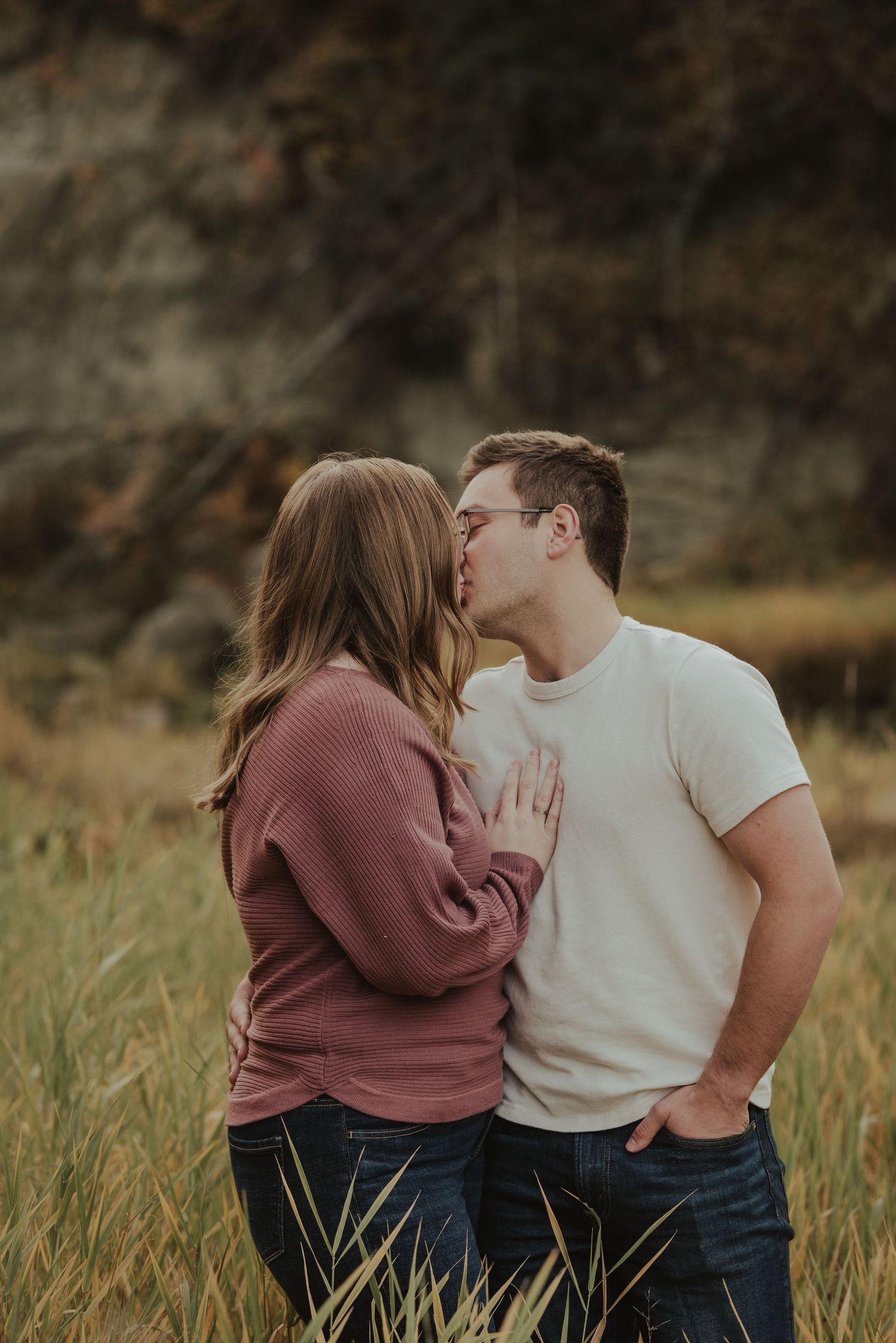Intimate moment between couple in casual wear standing in a golden field at dusk.