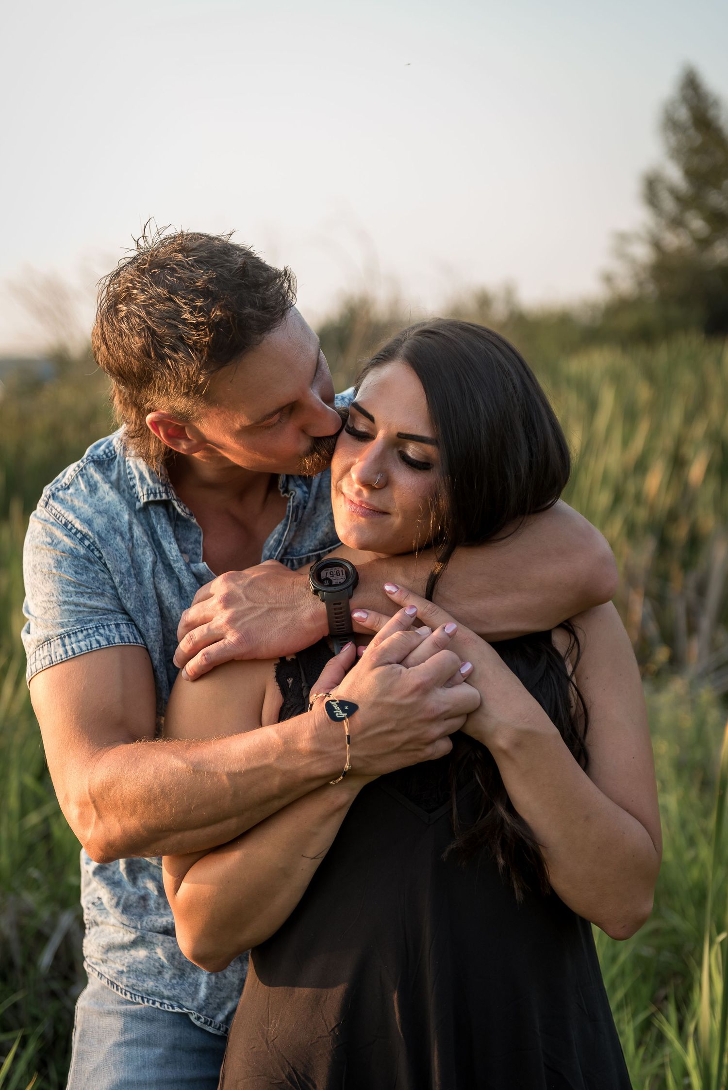 Romantic couple embracing in a sunlit field during golden hour.