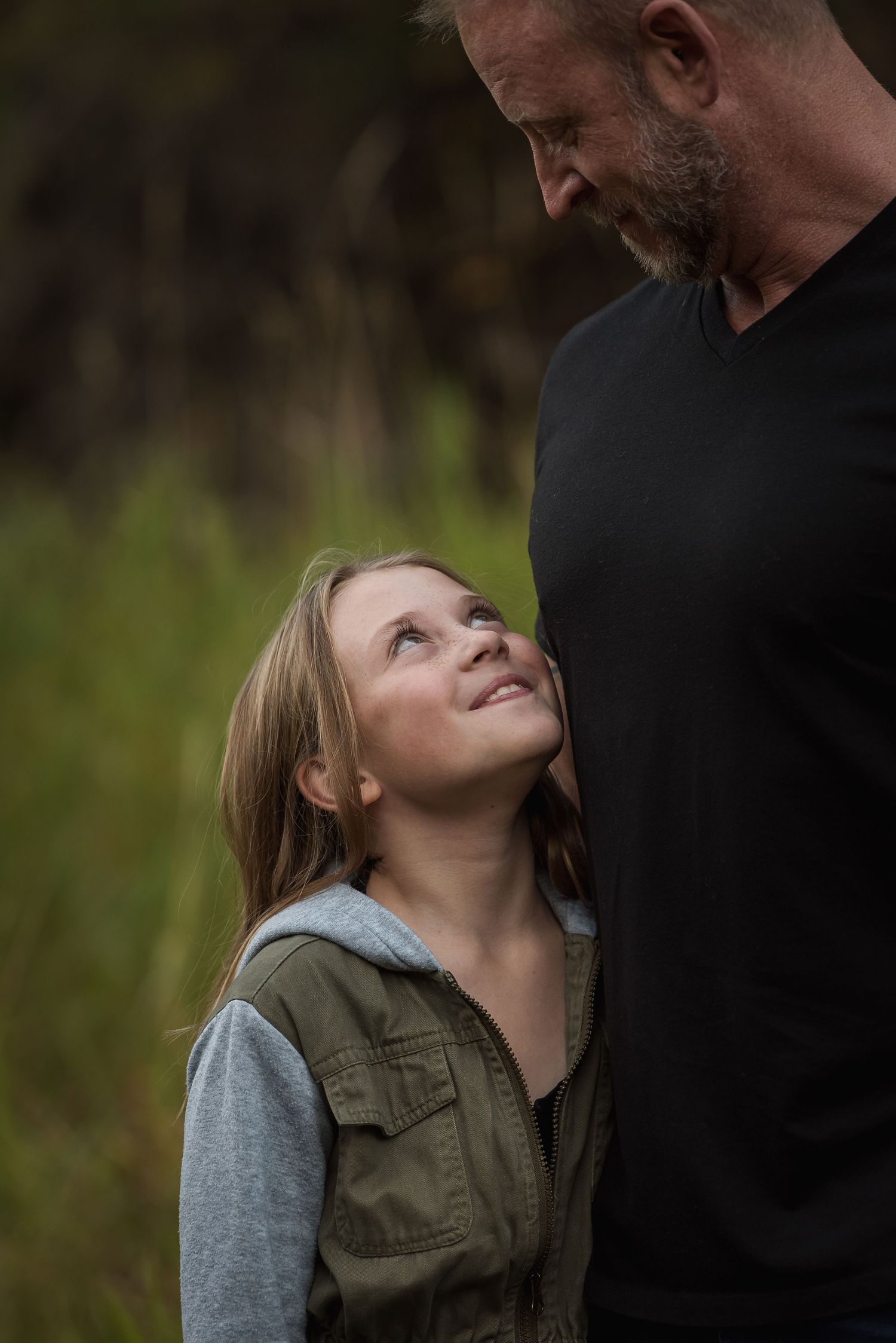 Parent and child sharing loving moment outdoors against natural background.