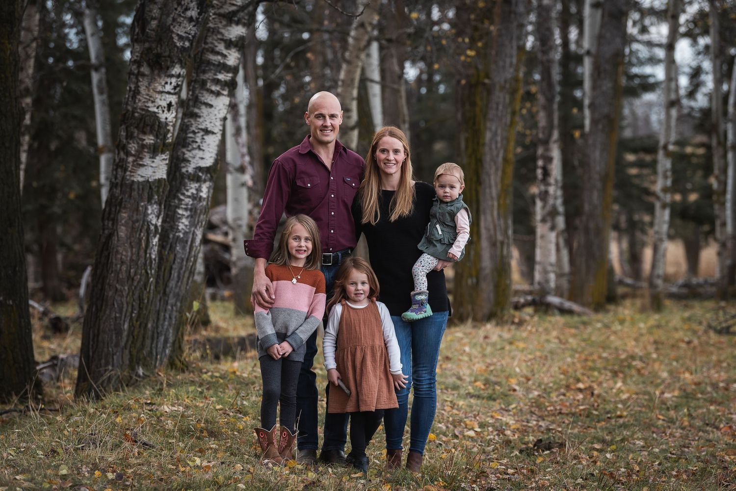 Family of five posing together in autumn birch forest.