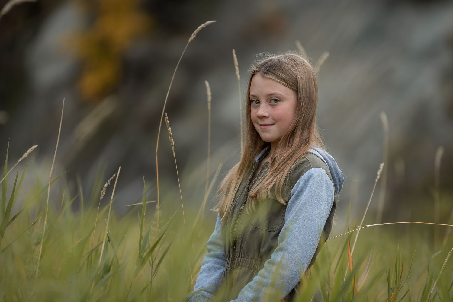 Young person sitting among tall grass during a warm afternoon.