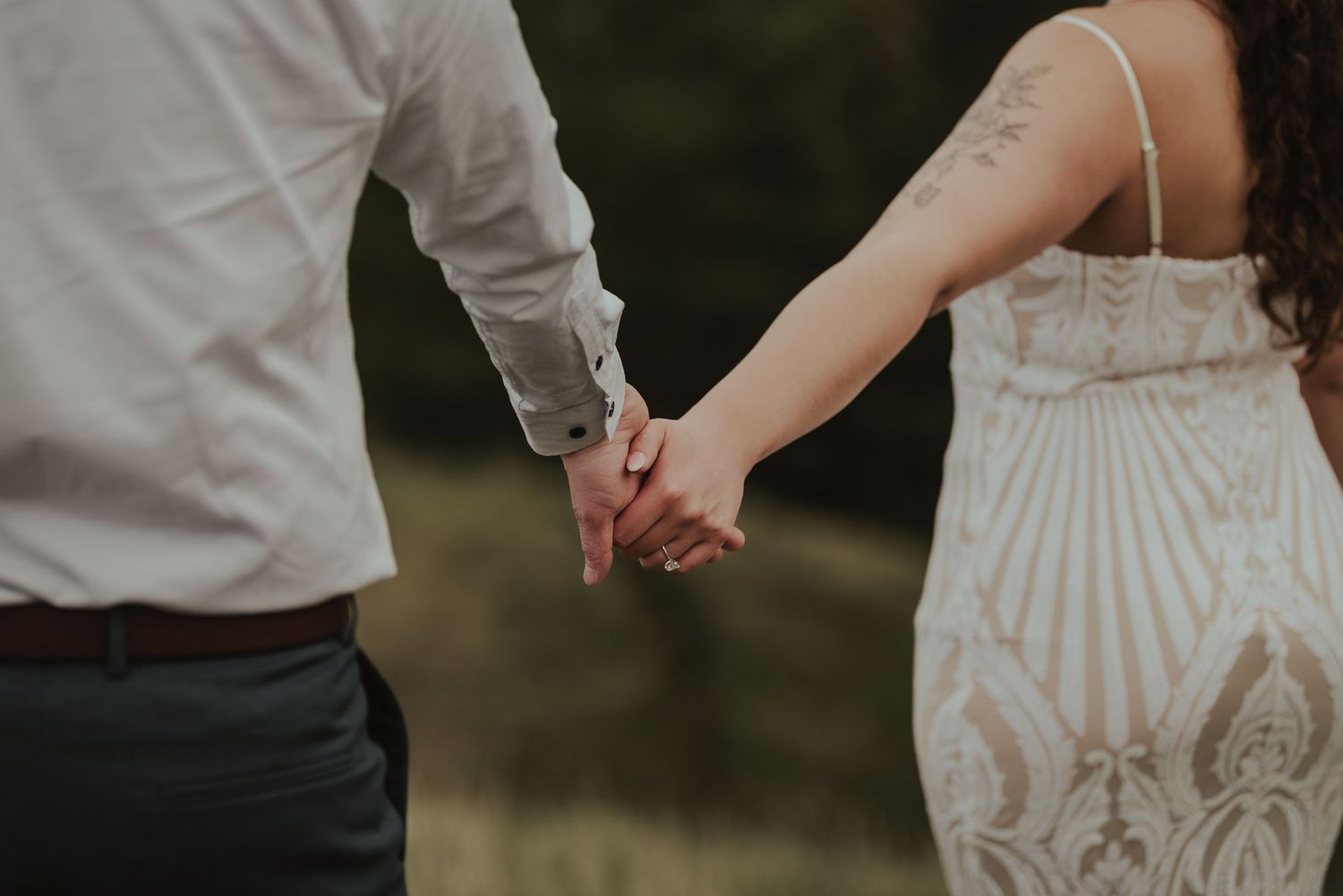 Close-up view of a couple holding hands against a natural outdoor background.