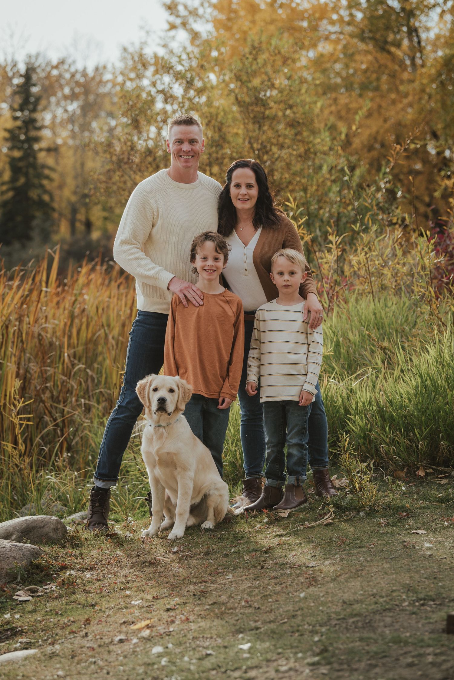 Fall family portrait with parents, two children and yellow lab on nature trail with autumn foliage.