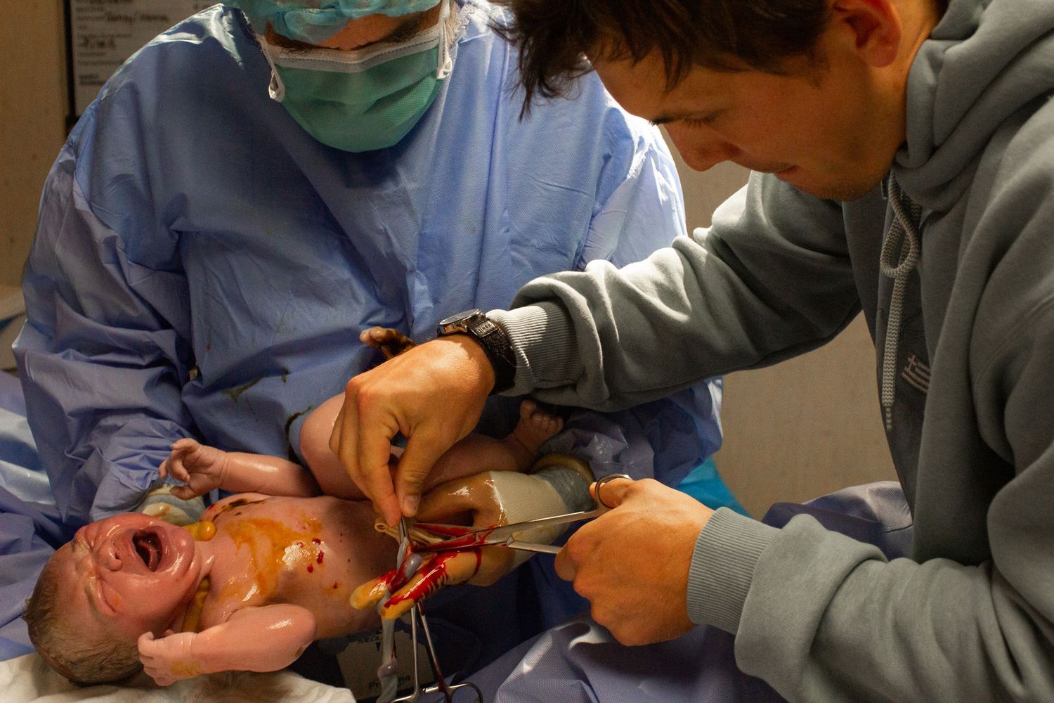 Medical team working together during delivery in hospital operating room.