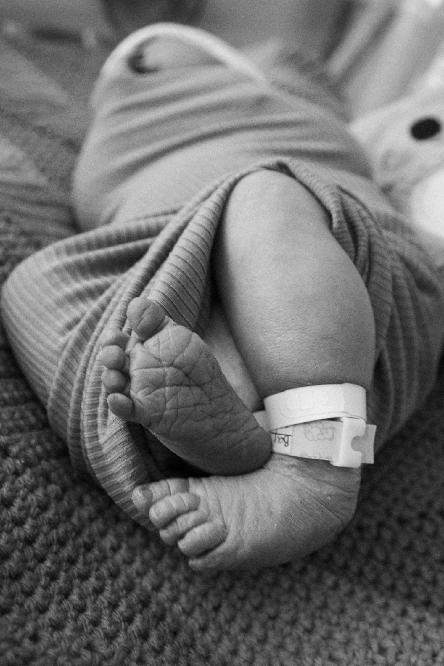 Black and white image of newborn feet with hospital ID band.
