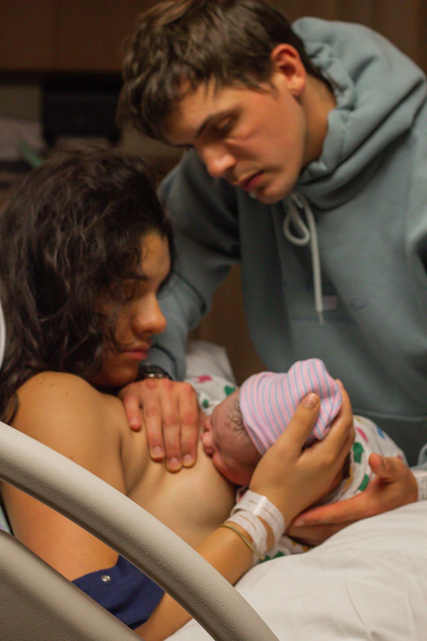Family sharing first moments with newborn baby in hospital room.