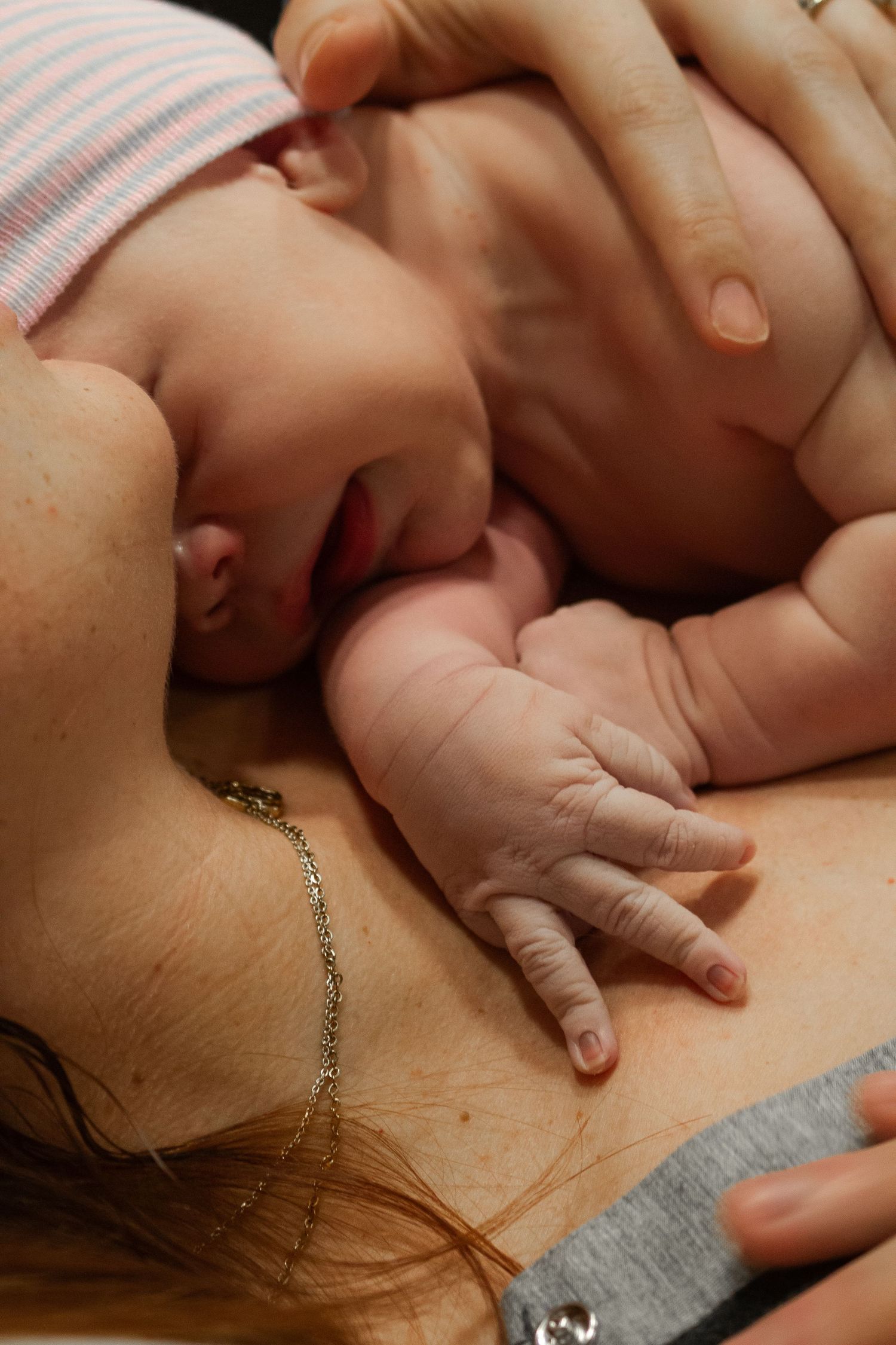 Newborn baby resting skin-to-skin with parent in intimate bonding moment.