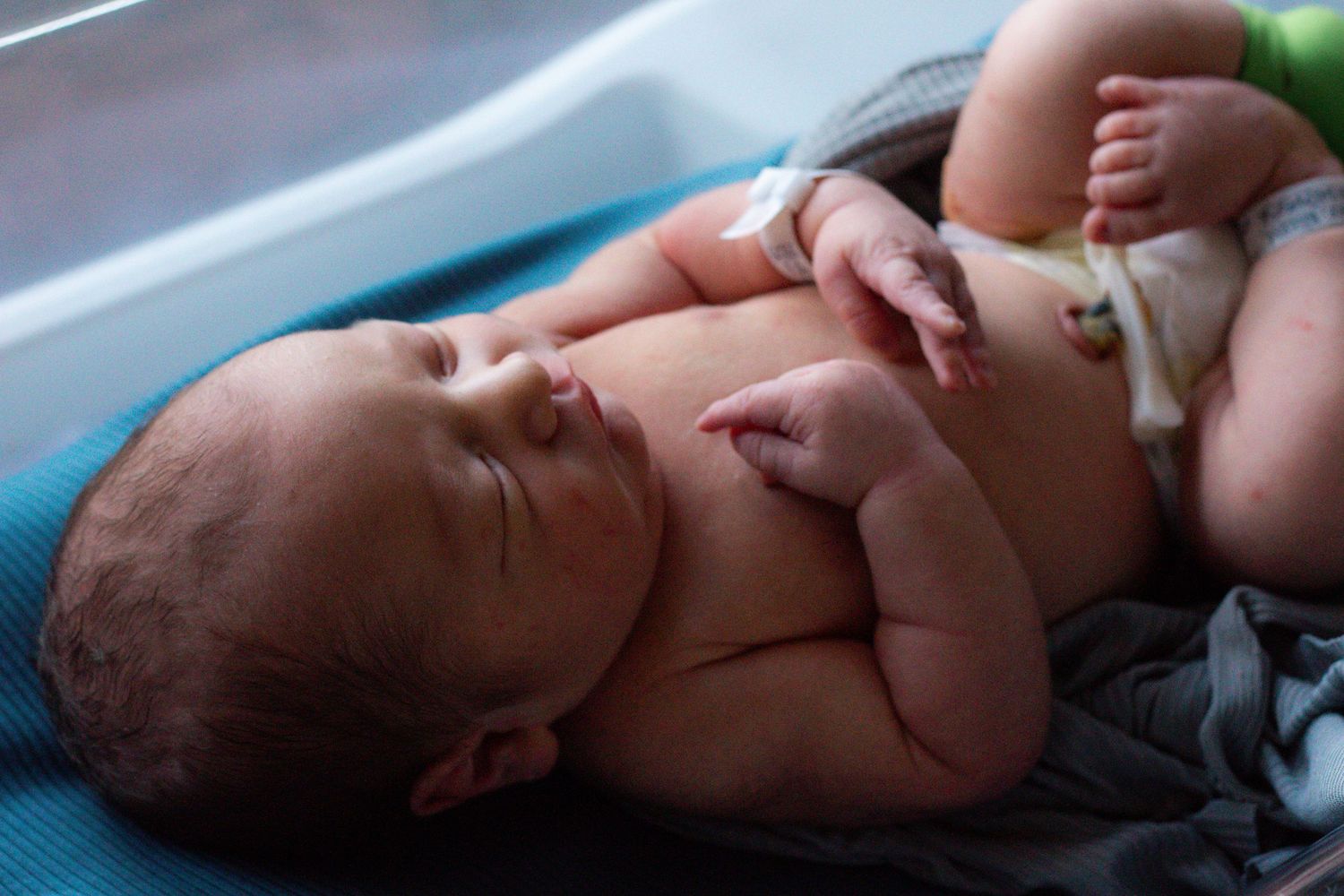 A resting newborn lies on a blue cushioned surface.