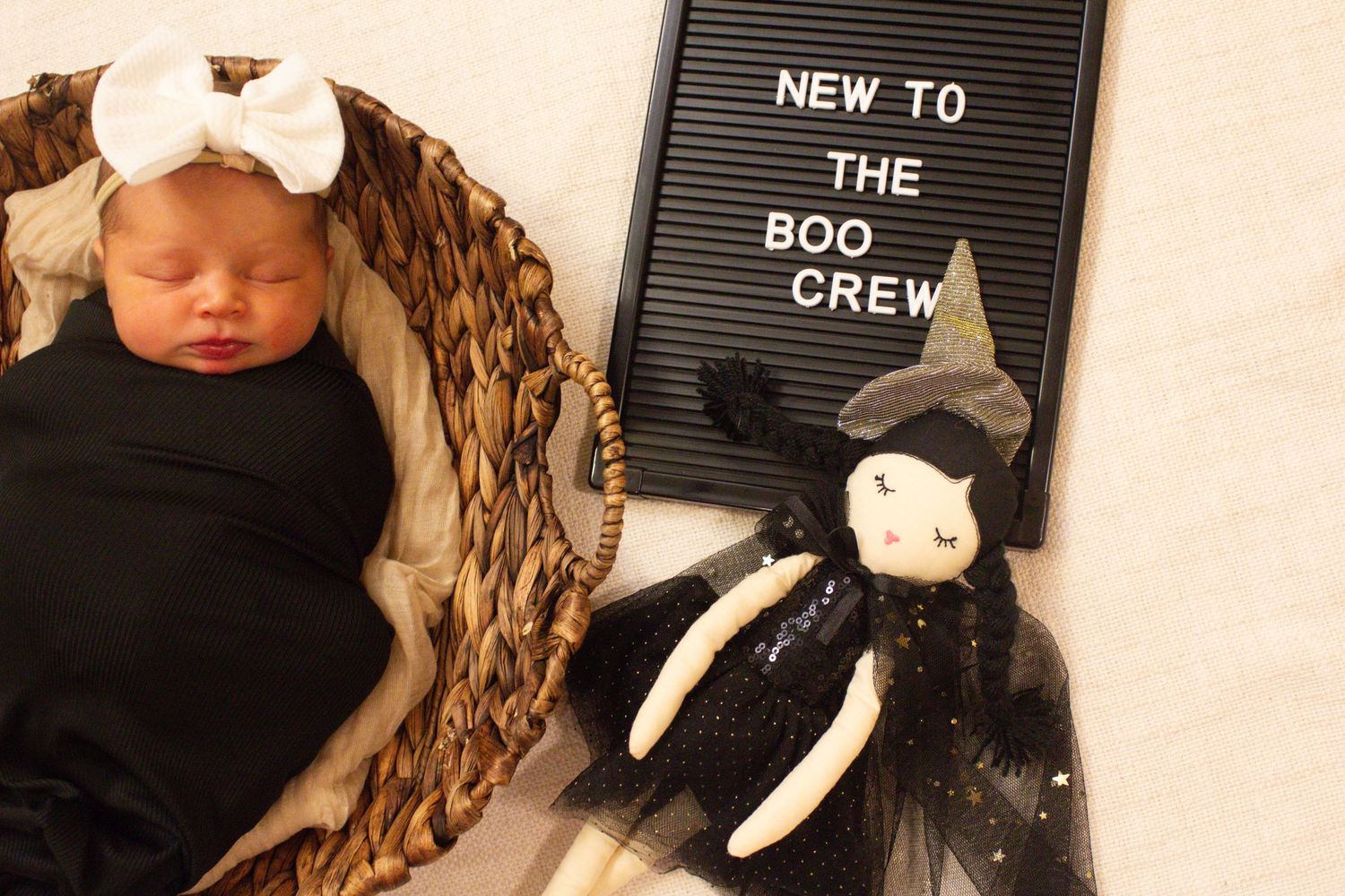 Sleeping newborn in basket beside letterboard and vintage style doll.
