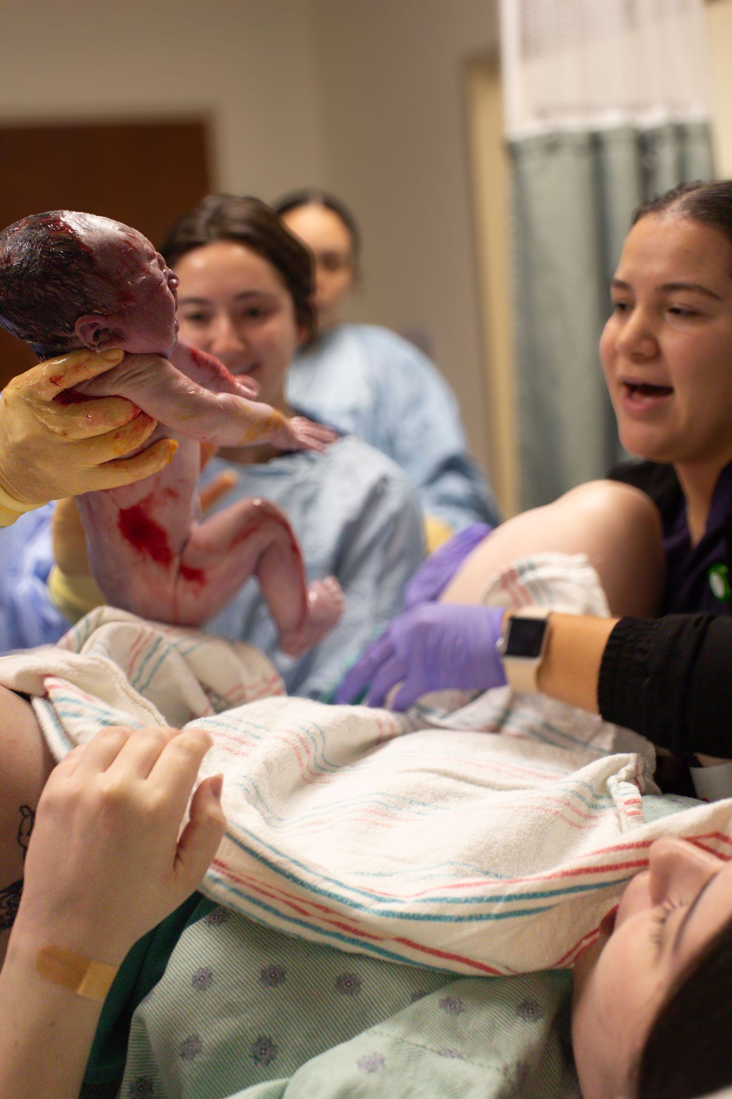 Medical staff presenting a newborn baby in a hospital delivery room.