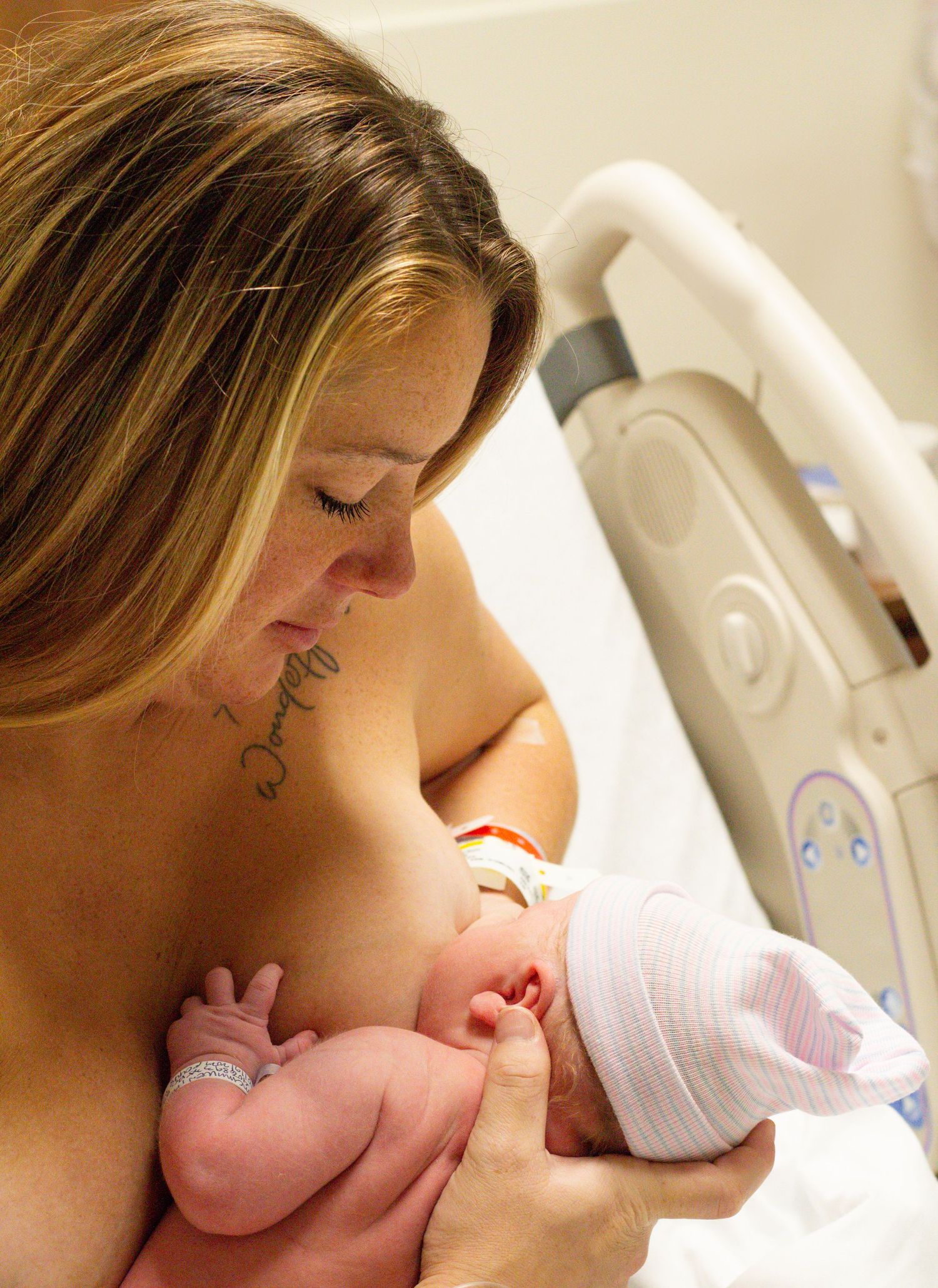 Mother and newborn sharing intimate skin-to-skin contact in hospital room.