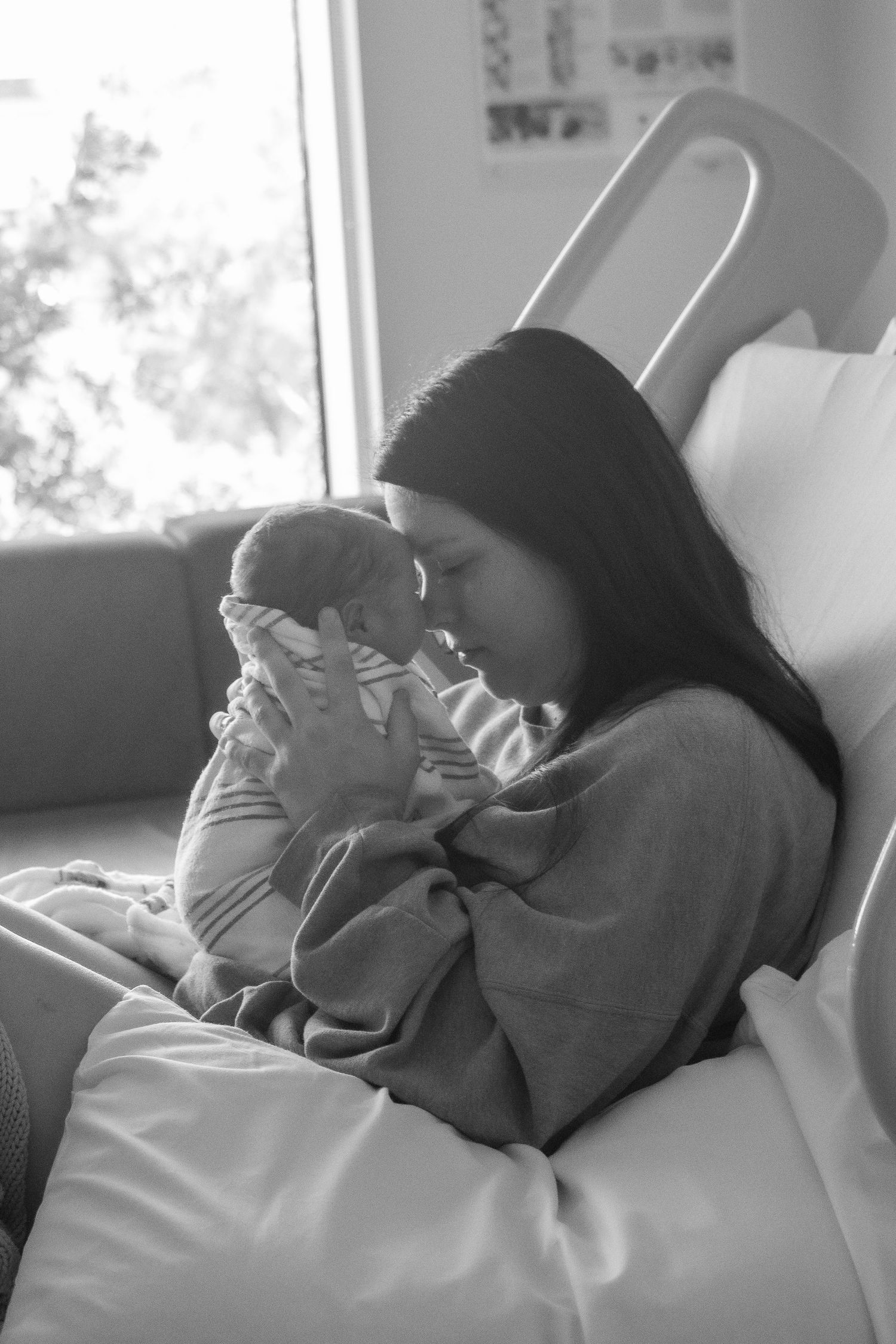 Black and white image of tender moment with newborn in hospital room.