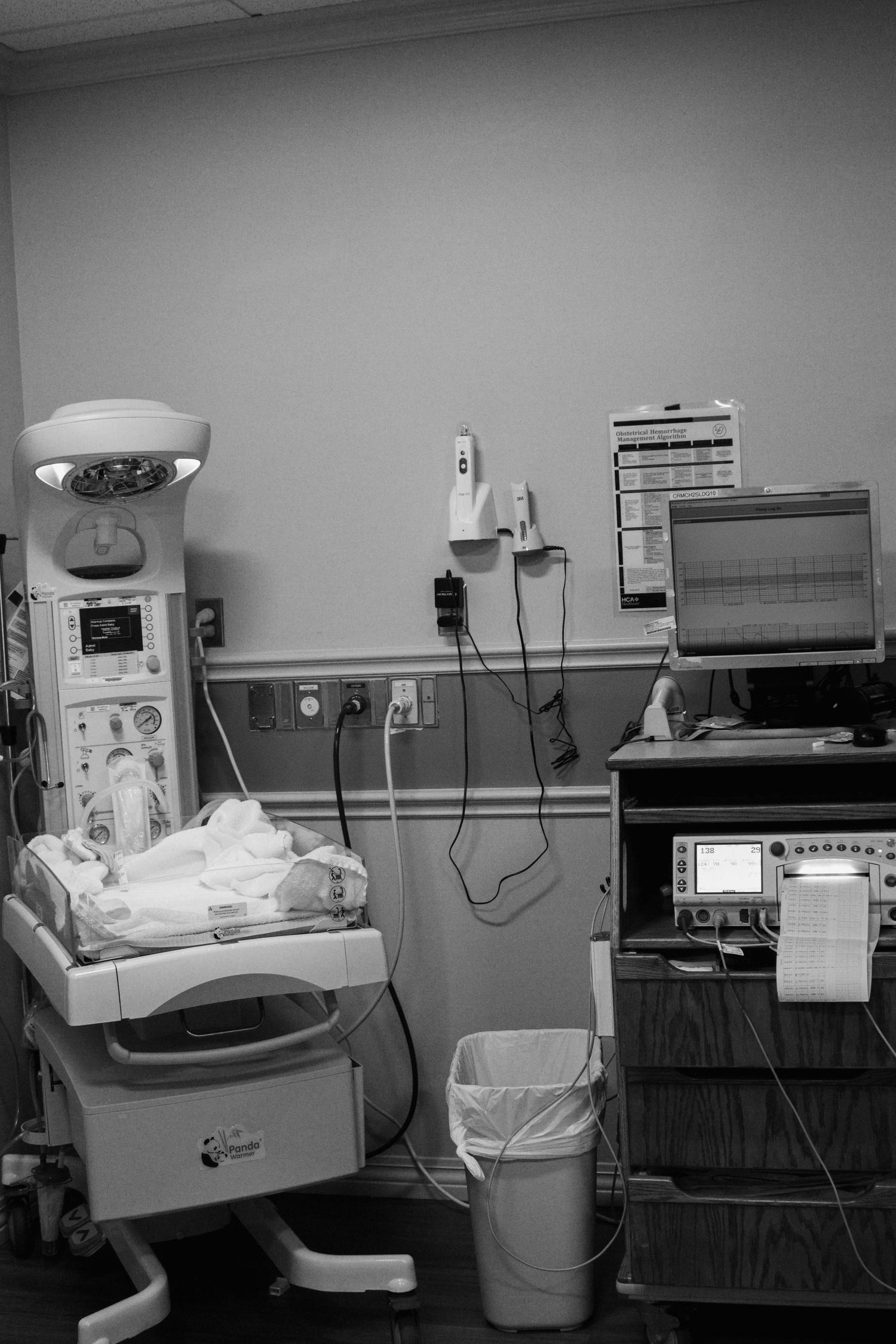Hospital room with medical equipment, including a baby warmer and monitoring system.