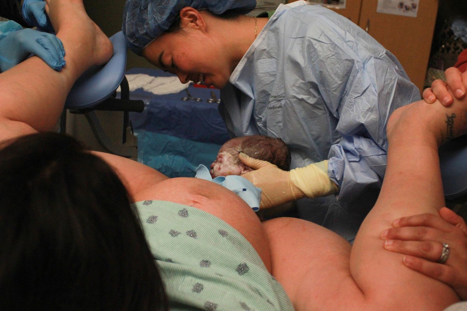 Healthcare workers attend to a patient during childbirth in a medical setting.