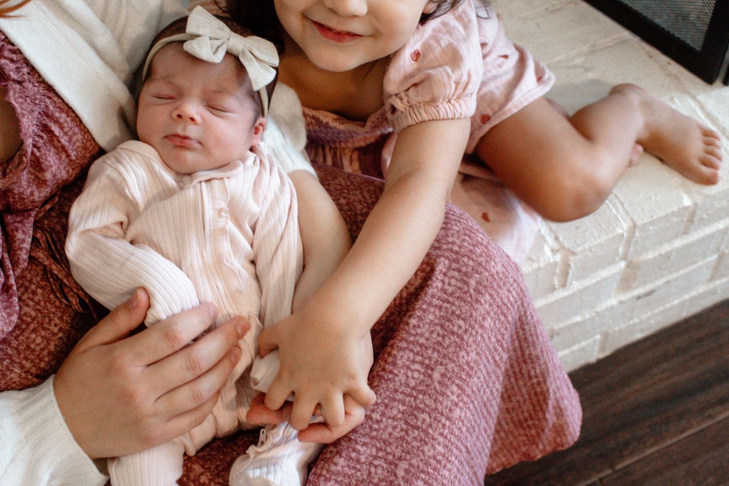 A baby in pink clothing with white bow resting peacefully on soft textiles.