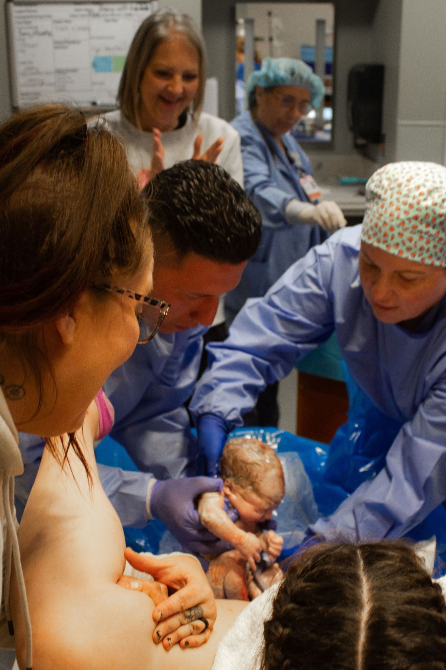 Medical team and family gather around during a hospital delivery procedure.