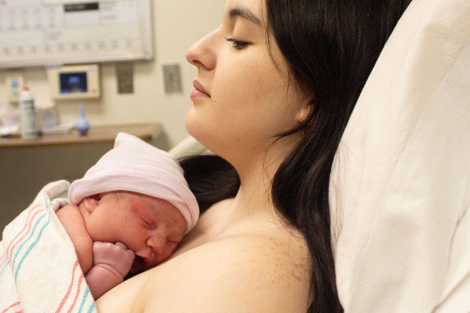 Peaceful skin-to-skin contact between mother and newborn in hospital setting.
