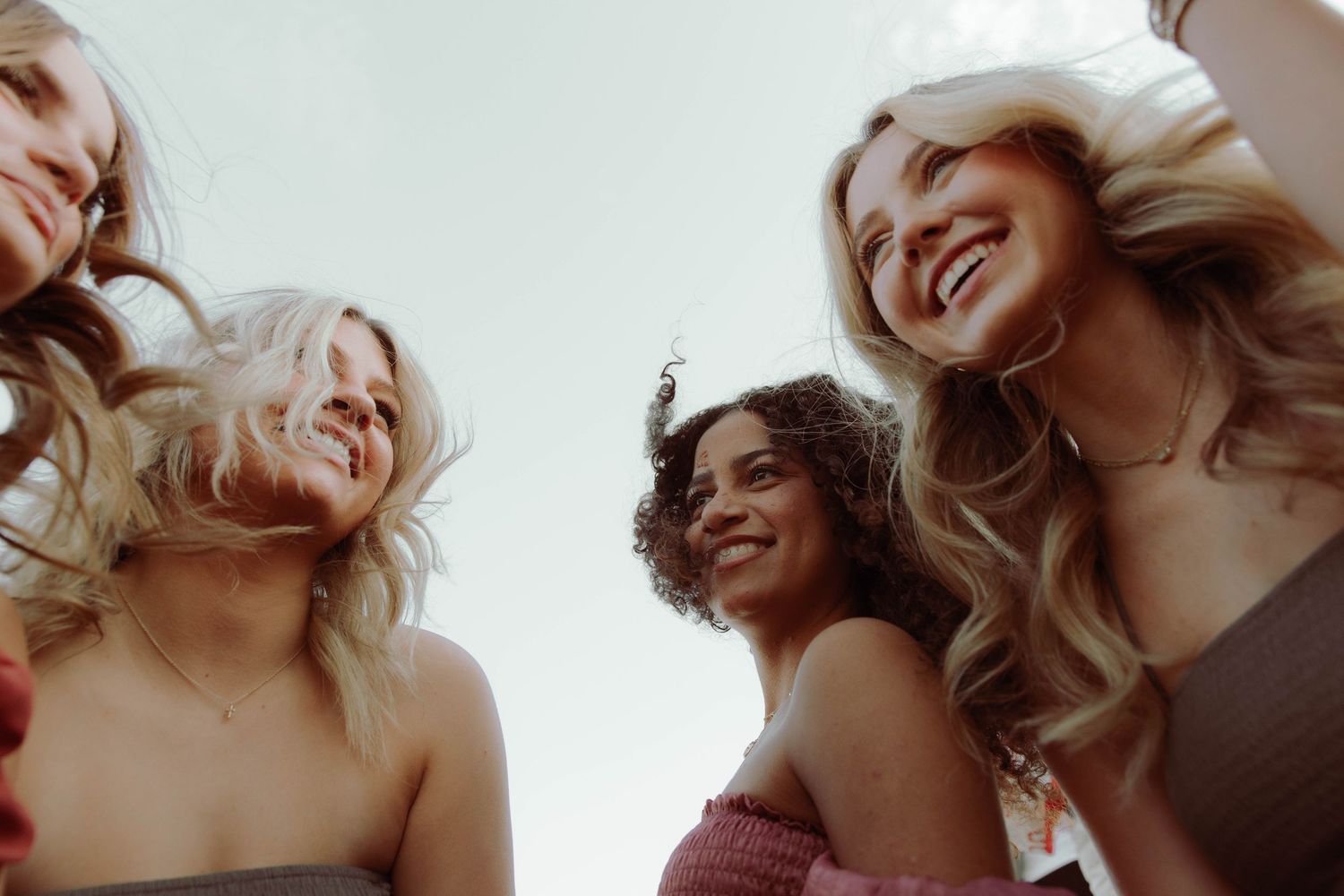 A series of eight connected portrait photos showing someone with blonde hair laughing and posing against a light background.